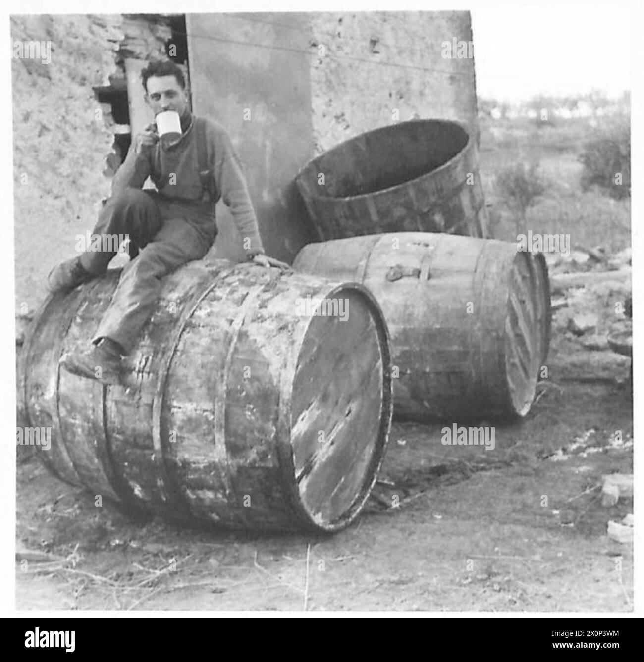 A soldier in an Eighth Army front-line village chooses tea over barrels of wine during operations in Italy. Stock Photo