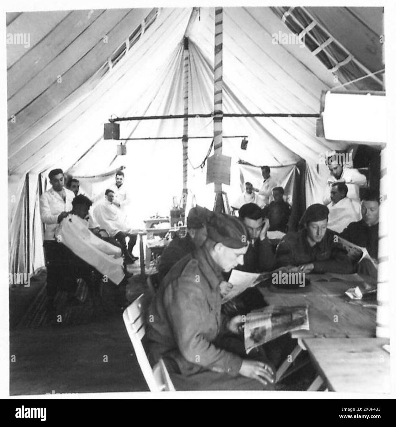 ITALY : FIFTH ARMY : 'THE CIRCUS' - While some of the men have the first comfortable haircut for weeks, others read while they wait their turn in the barbers shop. Photographic negative , British Army Stock Photo