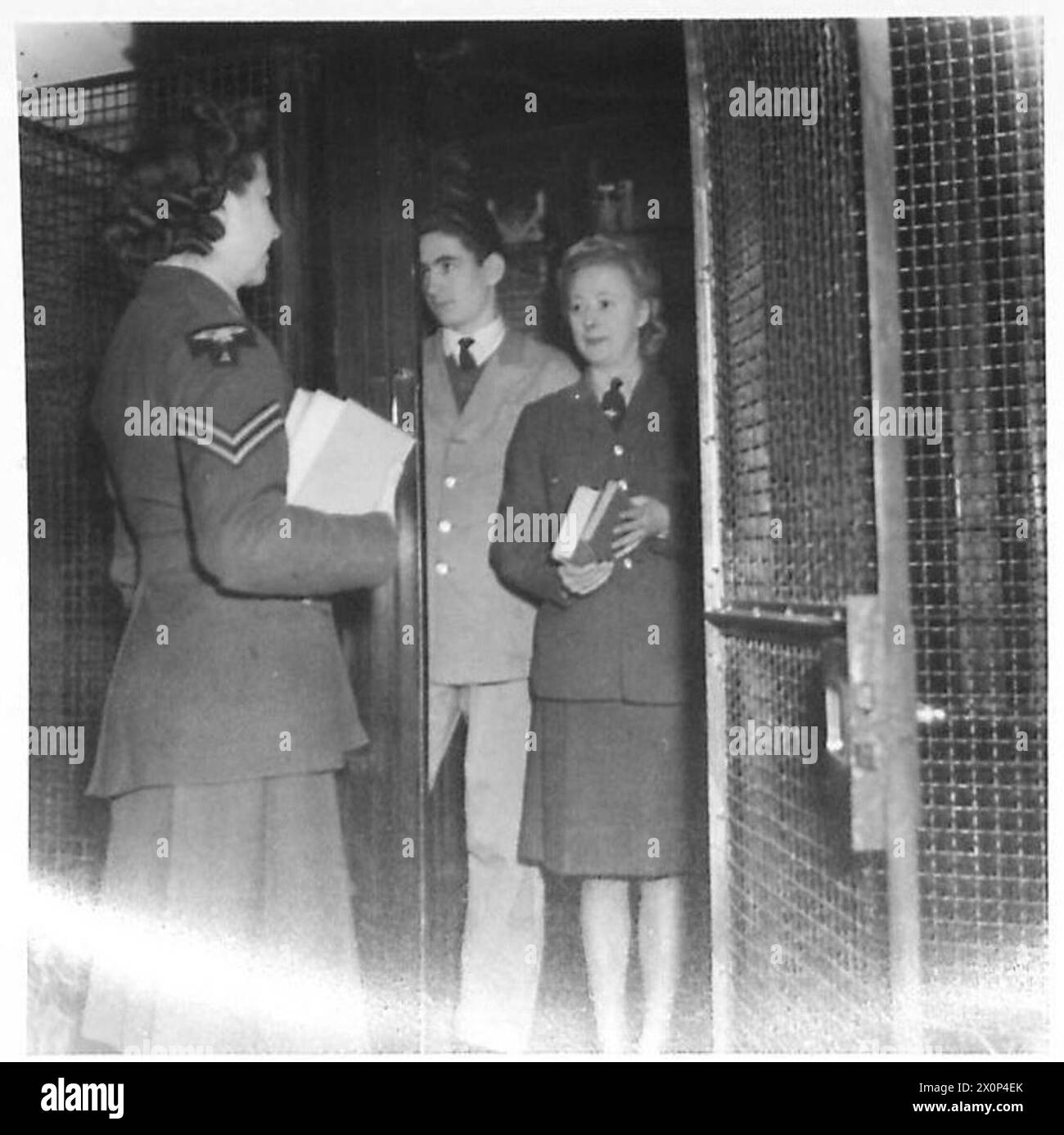Gladys and Ruby ascend the lift to their bedroom at the Y.W.C.A. Hotel, carrying books from the library to read before sleep. Photographic negative, British Army. Stock Photo