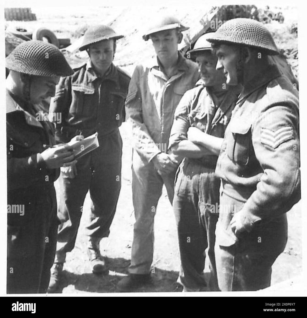 ITALY - ANZIO BRIDGEHEAD A MOBILE FIELD LAUNDRY - The O.C. of the platoon gives his orders to the Sections Sergeants. Left to right: - Capt. L.W. Cawley of Westover, Seaton Road, Axminster, Devon. Sgt. K. Clark of 1, Aubrey Road, Crouch End, London, N. Sgt. A.F. Wenborn of 182 Edward Street, New Cross, Lonfon, S.E.14. Sgt. E.H. Jones of 14 Church Lane, Bromley Common, Kent. Sgt. R. Gowland of 103 Juliet Street, Ashington, Northumberland. Photographic negative , British Army Stock Photo