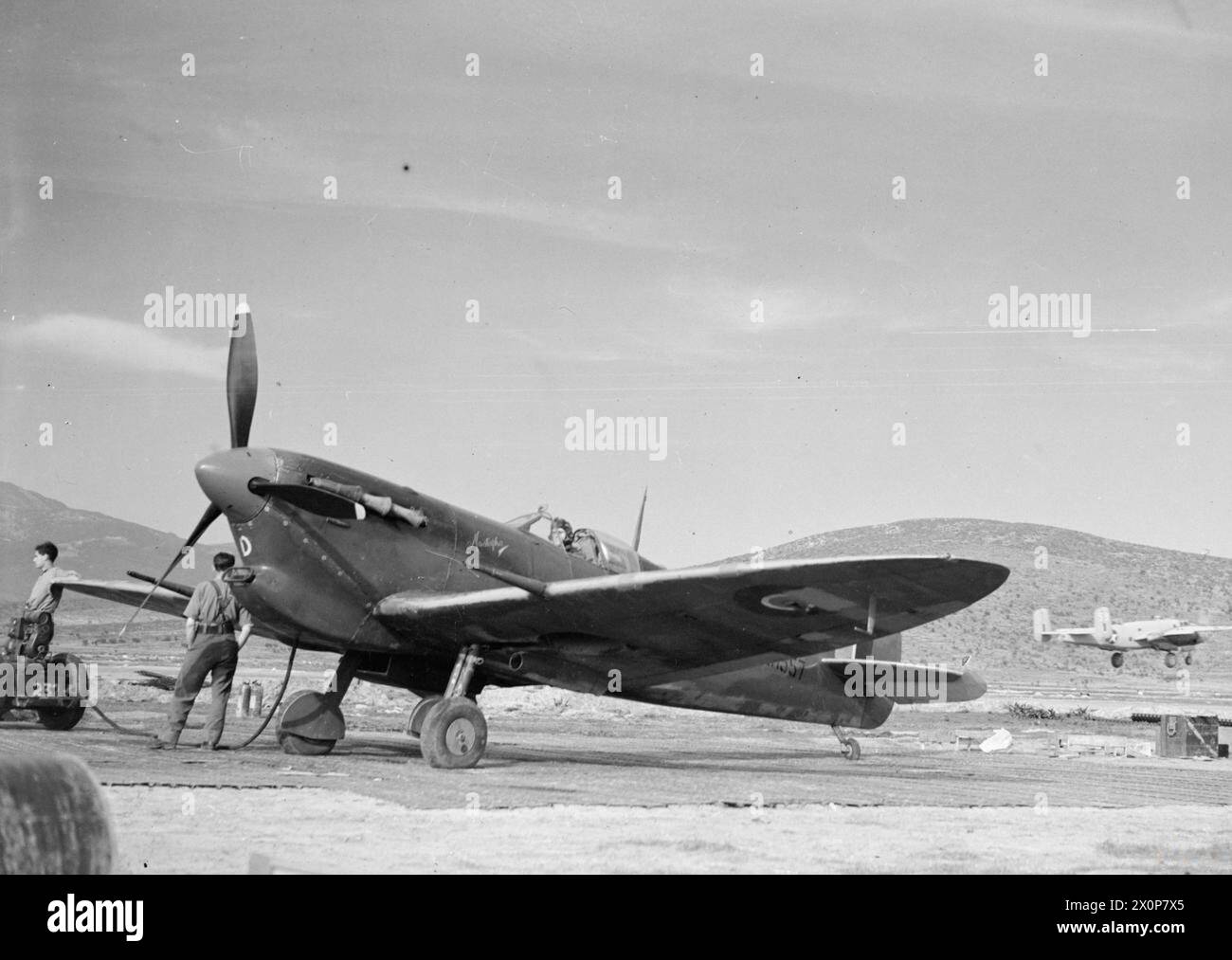 ROYAL AIR FORCE OPERATIONS IN THE MIDDLE EAST AND NORTH AFRICA, 1939-1943. - Supermarine Spitfire Mark VC, ER557 'EF-D' 'Mustapha', of No. 232 Squadron RAF awaits the signal to start up in its dispersal at Tingley, Algeria. It formed part of the fighter escort for a force of North American B-25s of the 12th Bombardment Group Detachment USAAF, one of which can be seen taking off at right Royal Air Force, Maintenance Unit, 233, United States Army Air Force, 12th Bombardment Group Stock Photo