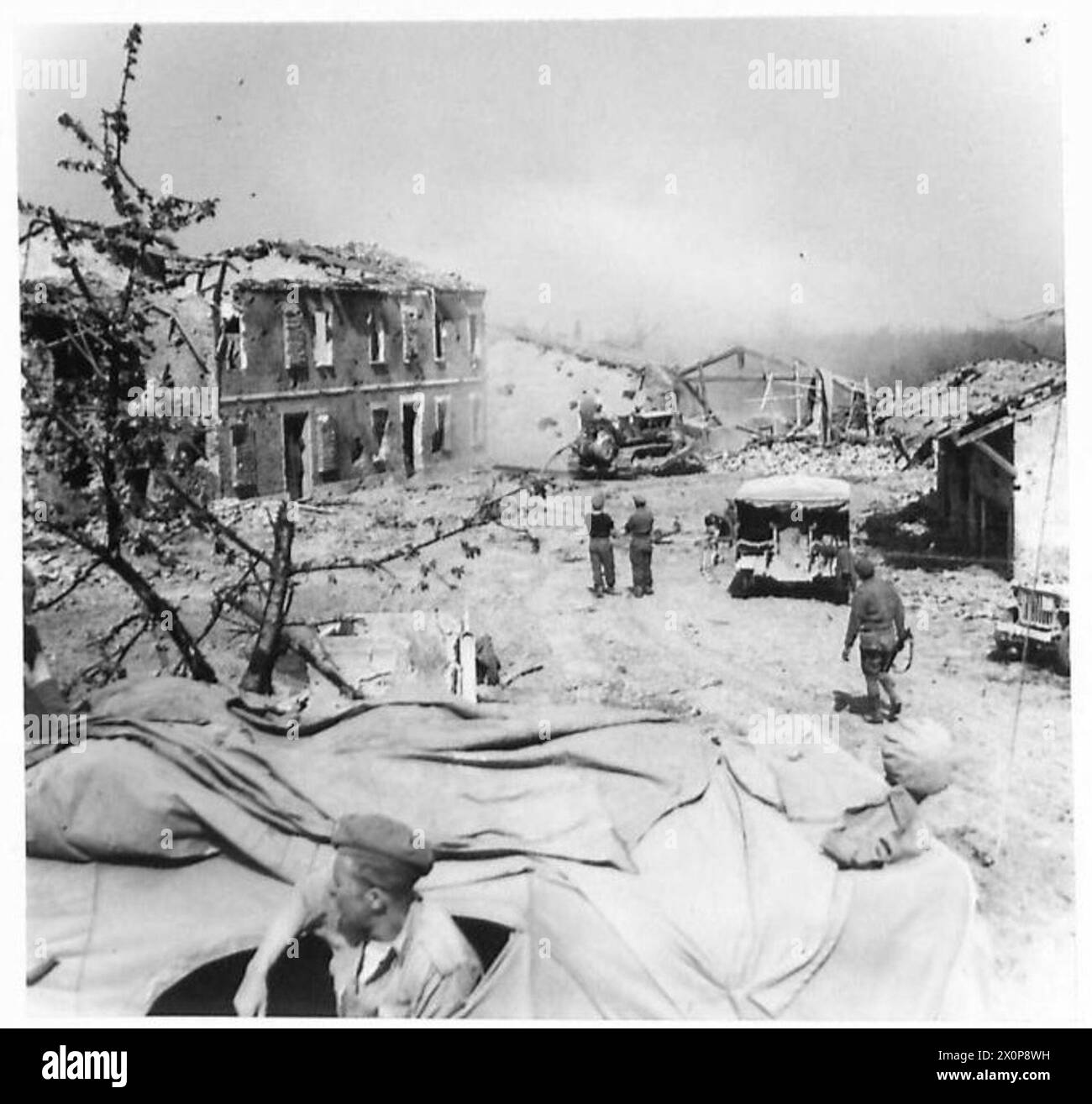 Bulldozers of the Eighth Army demolish a shattered farm wall beyond the River Senio to provide materials for road repairs in a former German front line heavily damaged by air and artillery attacks. Photographic negative. Stock Photo