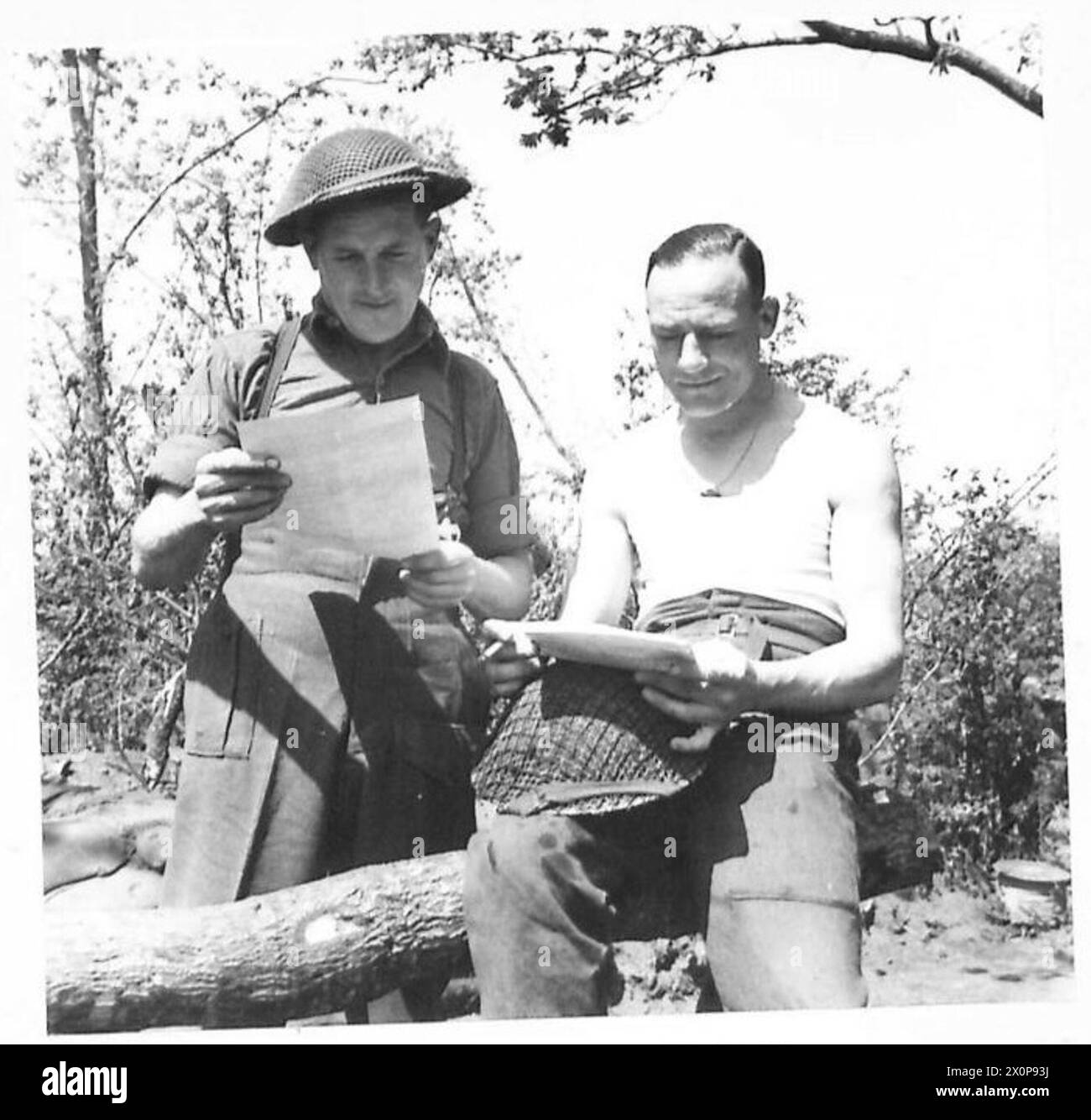 FIFTH ARMY : ANZIO BRIDGEHEAD - VARIOUS - - Sgt. T. Hodder (left) of 66 Marville Road, Fulham, S.W.6 and Sgt. H. Hastings of 32 Culpepper Street, Finsbury, London, N.l. reading the local paper, a duplicated sheet called 'The Beachead News'. It contains the BBC news report, and full reports of local patrol activity. Photographic negative , British Army Stock Photo