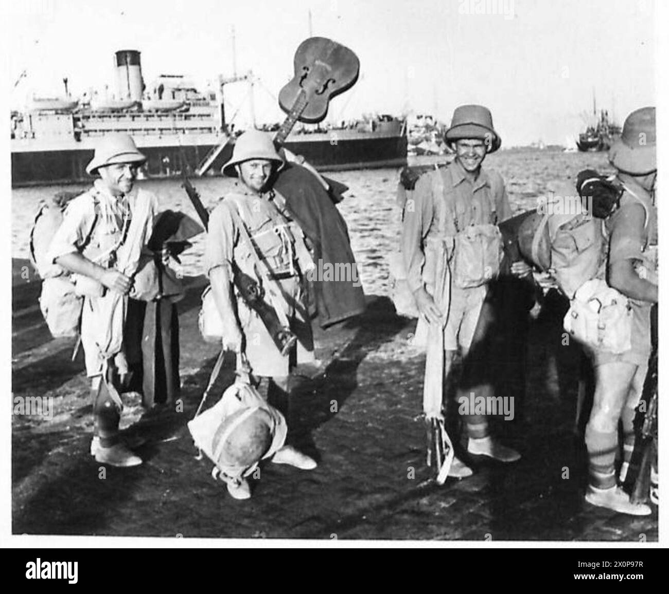 THE POLISH ARMY IN THE SIEGE OF TOBRUK, 1941 - Cheerful soldiers of the Polish Independent Carpathian Rifles Brigade waiting in line, ready to board one of the Royal Navy destroyers. One of them showing his guitar he made sure to take with him. Photograph taken on a quayside of the port in Alexandria. The Brigade was transferred to Tobruk in seven convoys between 19 and 28 August 1941 Polish Army, Royal Navy, Polish Armed Forces in the West, Independent Carpathian Rifles Brigade Stock Photo