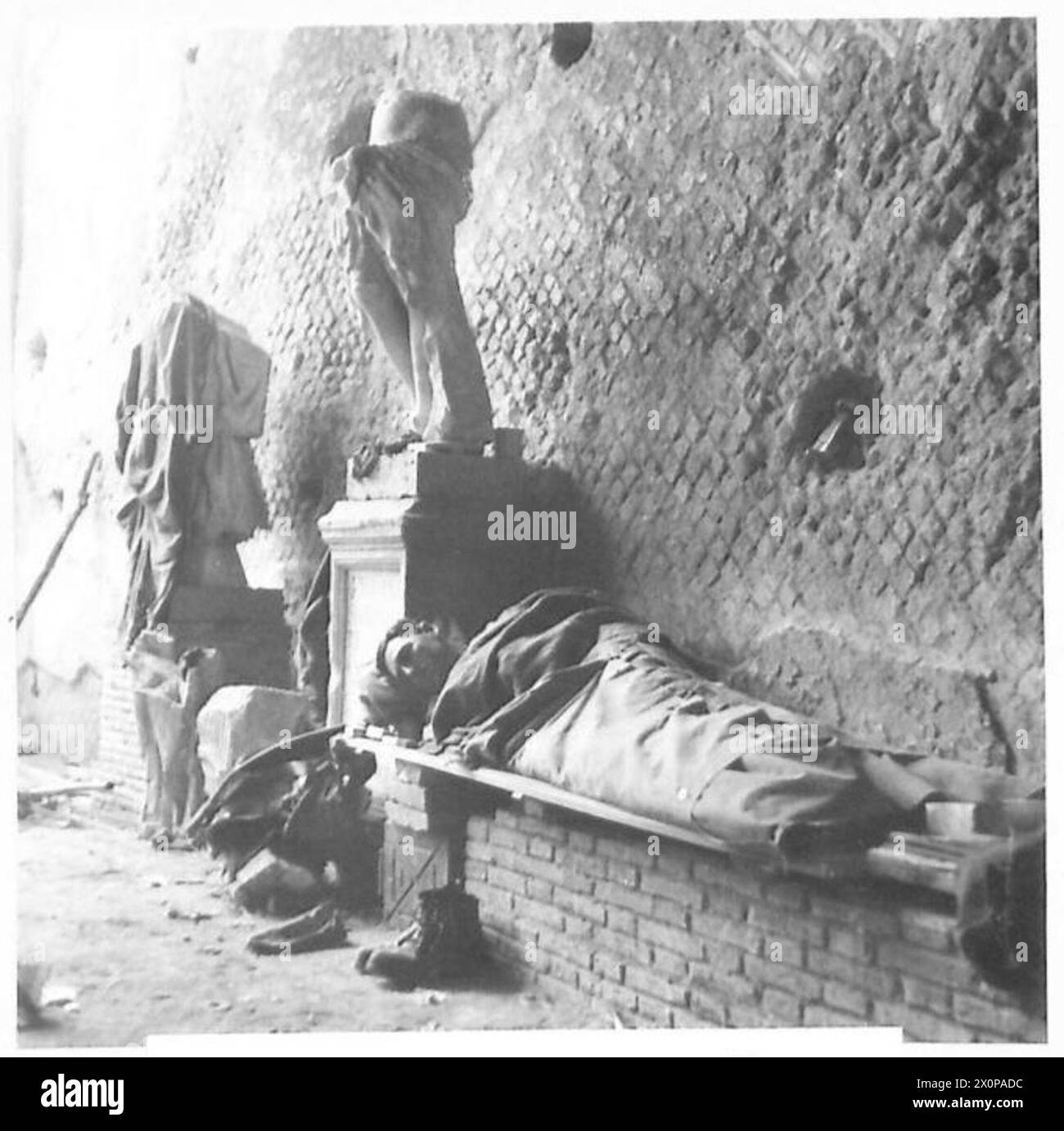 THE BRITISH ARMY IN NORTH AFRICA, SICILY, ITALY, THE BALKANS AND AUSTRIA 1942-1946 - After a night patrol activity, Rfn. H. Stanborough of Wlathamstow, London, sleeps contentedly under the shadow of a statue. Photographic negative , British Army Stock Photo