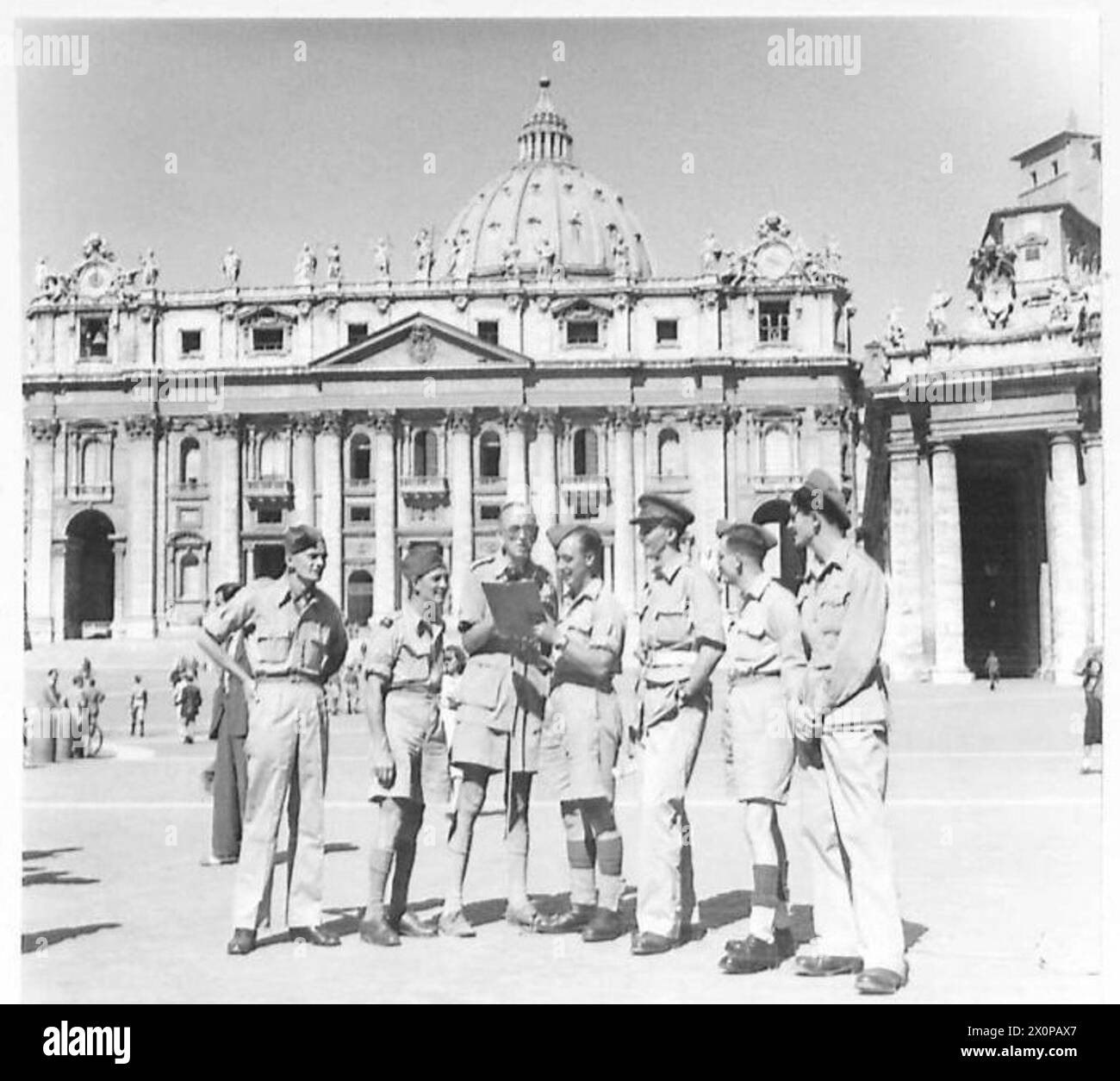 ITALY : B.B.C. RECORDING VAN - A group of 6 NCOs and men, with Major Haddon of the B.B.C. in front of St. Peter's Church. They are, left to right:- L/Cpl. E. Turner of 10 Rayleigh Road, Woodford Green, E.18. S/Sgt. G. Little of 61 Kent Avenue, Leigh-on-Sea, Essex Dvr. W.A. Clark of Trinity Church, Huntingdon Dvr. J.H. Rennison of 3 Claremont Avenue, Maghull, near Liverpool L/Cpl. F.G. Manvell of 72 Camden Road, Tunbridge Wells, Kent and Pte. Nat Selby of 19 Back Street, Biggleswade, Beds. Photographic negative , British Army Stock Photo