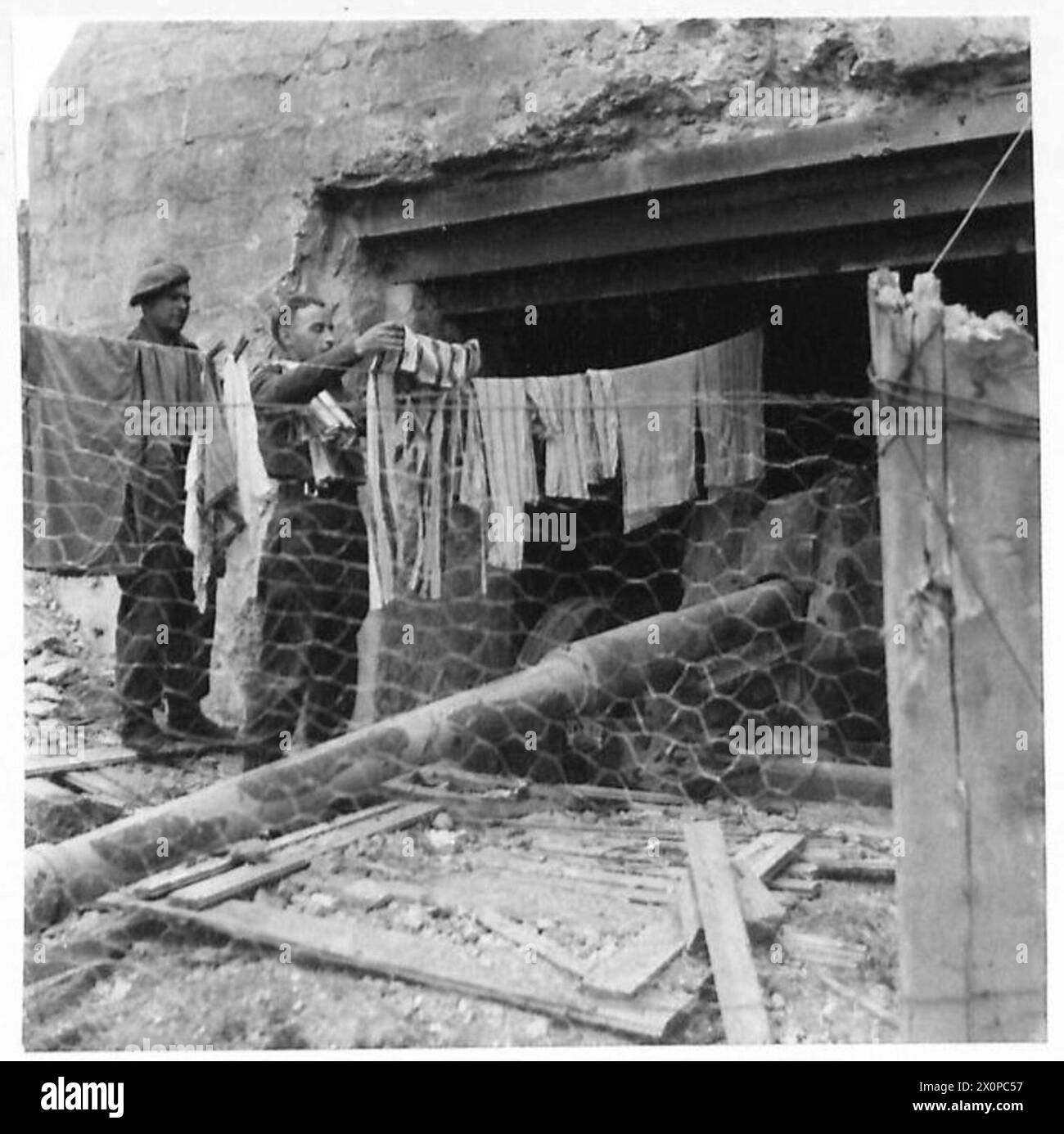 ALLIED FORCES IN THE NORMANDY CAMPAIGN 1944 - British troops hang their washing in front of a knocked-out German gun emplacement at Courseulles-sur-Mer, 11 June 1944. This Type 677 concrete emplacement was part of the WN-29 strongpoint at Courseulles. The gun is an 8.8cm Pak 43/41 Stock Photo