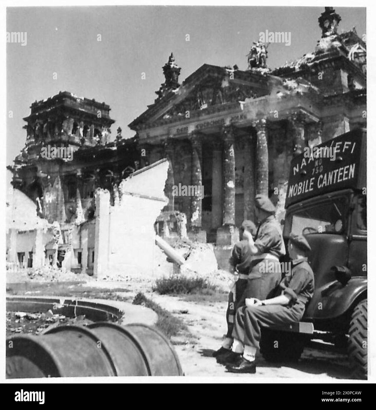 REQUEST BY P.R. N.A.A.F.I. - CSM J. WALKER - NAAFI MOBILE NO. 750 THE FIRST CANTEEN INTO BERLIN - Three Tommies discuss the history of the Reichstag over a cup of tea. Photographic negative , British Army, 21st Army Group Stock Photo