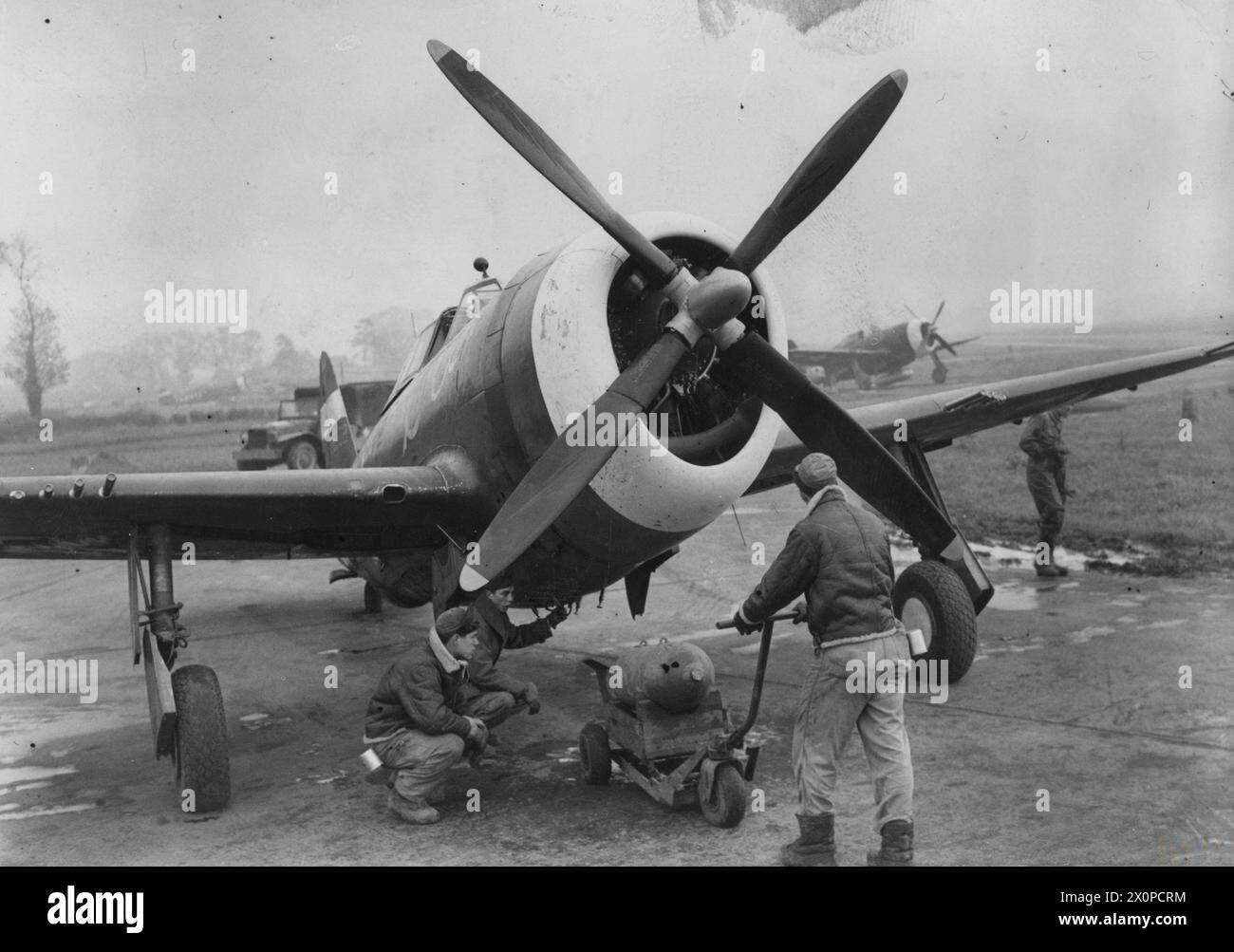 Ground crew of the 353rd Fighter Group prepare to attach a bomb to a P ...