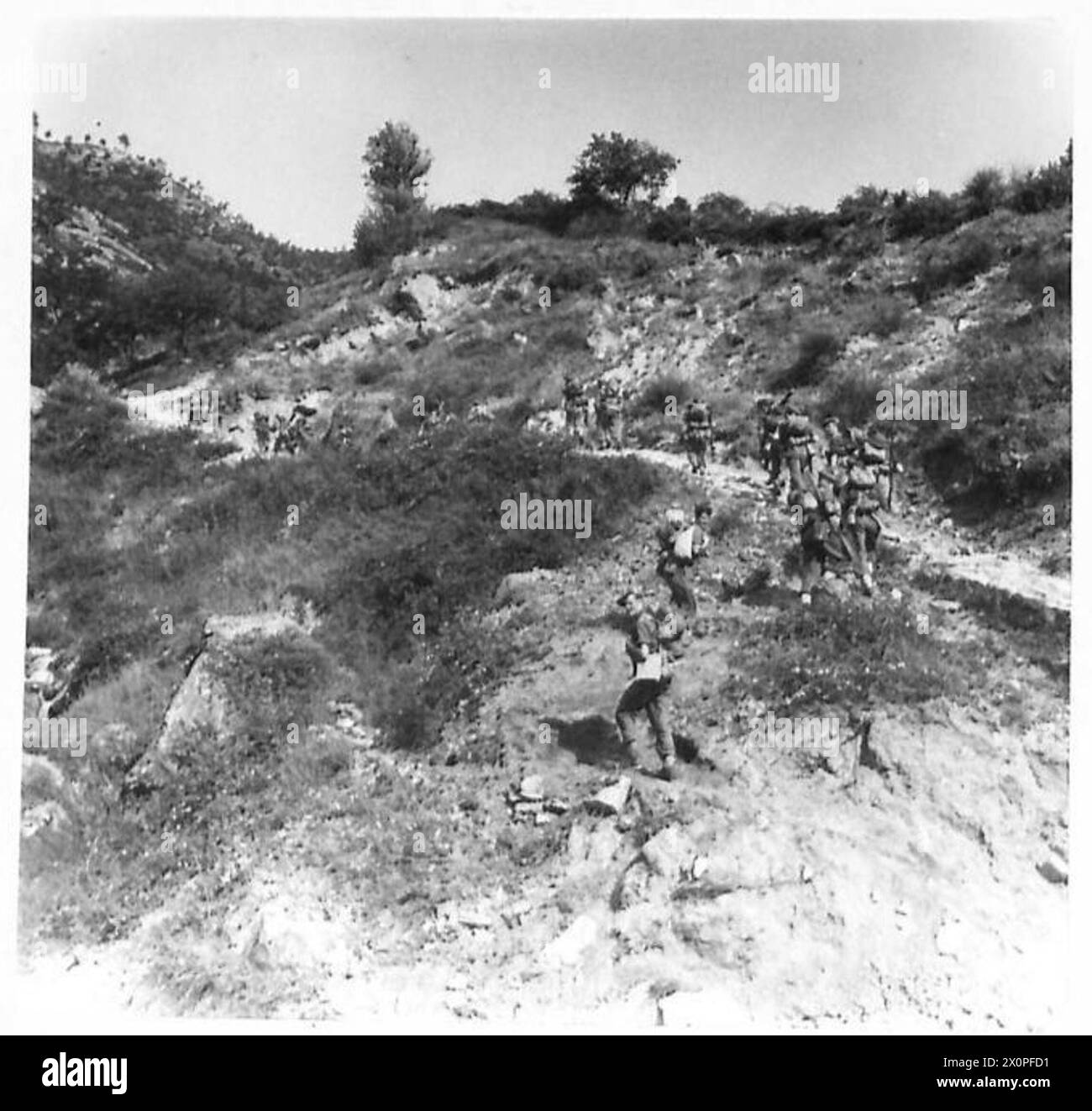 Eighth Army infantrymen leave the road and ascend a rough track on a steep mountainside to reach front line positions. Stock Photo