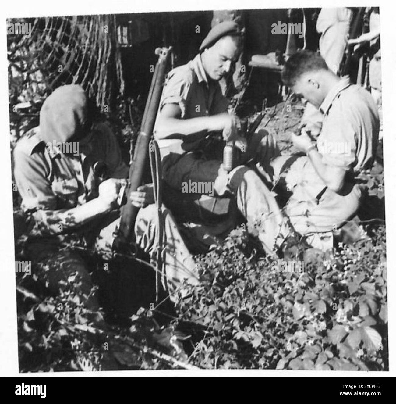 FIFTH ARMY : VARIOUS - Tpr. J. Burke of Hamilton, Scotland (left), Tpr. H. Gregory of 228 Sebert Road, Forest Gate, London, E. 7 and Dvr. M.A. Witcombe of 3/133 George Street, West Brookfields, Birmingham, 18 clean their weapons before setting out for the concentration area. Photographic negative , British Army Stock Photo
