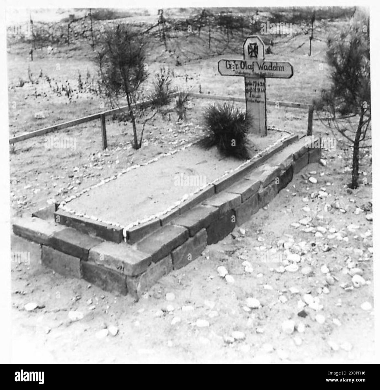 A German soldier's grave, aged 20, located near defensive structures including barbed wire and pillboxes, illustrating the wartime conditions around an airfield prepared by the Eighth Army. Photographic negative, British Army. Stock Photo