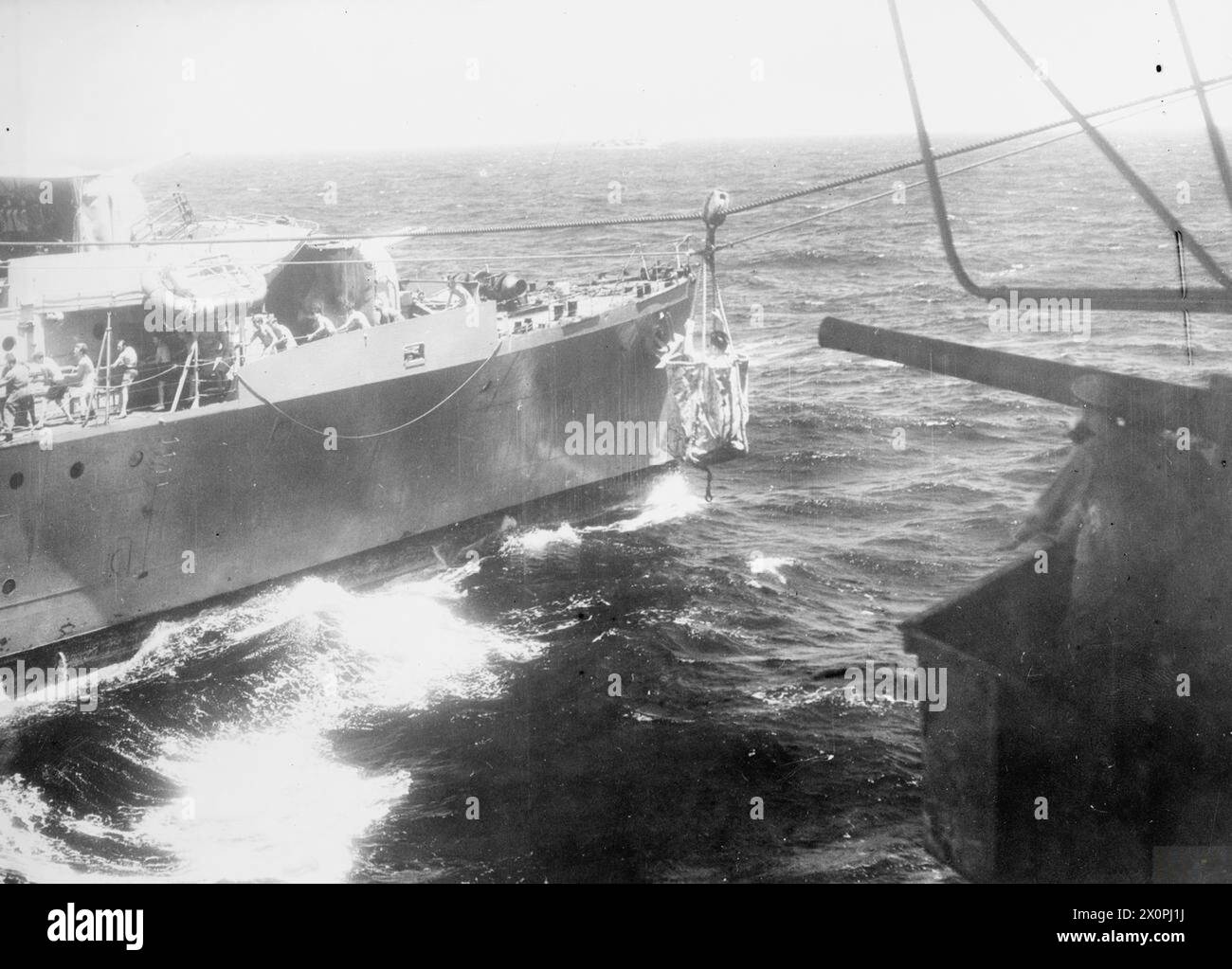 WITH THE BRITISH PACIFIC FLEET CARRIER HMS SMITER AT SEA. MAY 1945, DURING THE OPERATIONS AGAINST SAKISHIMA IN SUPPORT OF THE AMERICAN LANDING ON OKINAWA. - War correspondent A C McWhinnie being ferried from the replinishment carrier to a destroyer during the first battle for the Japanese homeland when the BPF supported the American attack on Okinawa by a covering action on the Sakashima Gunto Stock Photo