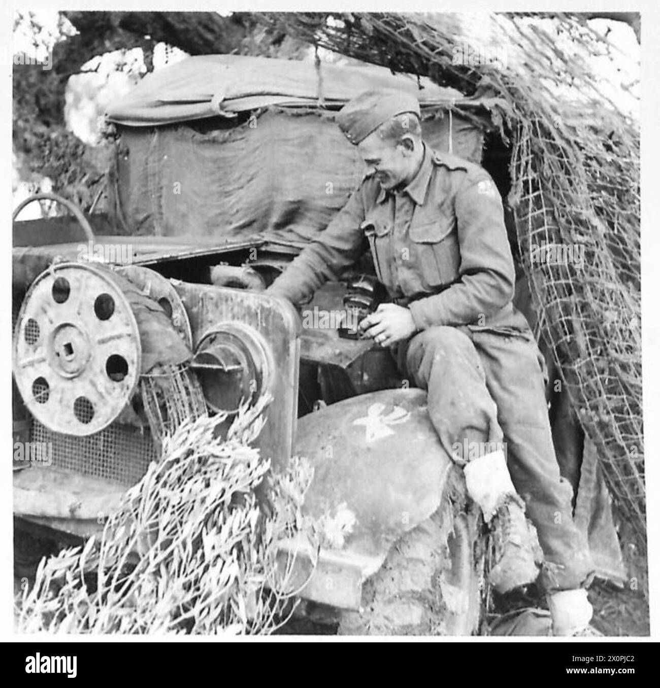 NEWFOUNDLAND GUNNERS IN ITALY - Dvr. H. Oke, of Corner Brook, Newfoundland, at work on his truck. Note the Newfoundland caribou on the mudguard. Photographic negative , British Army Stock Photo