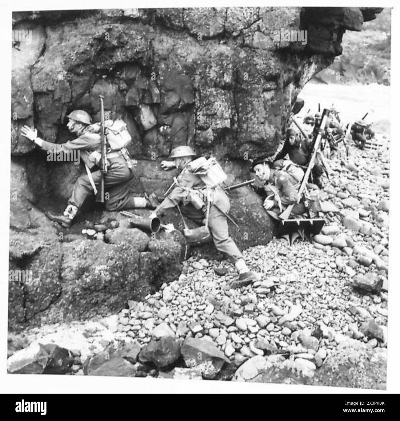 BRITAIN�S SHOCK TROOPS - Infantry making their way over the rocky shore with their heaviest weapon, the three inch mortar, and ammunition. Photographic negative , British Army Stock Photo