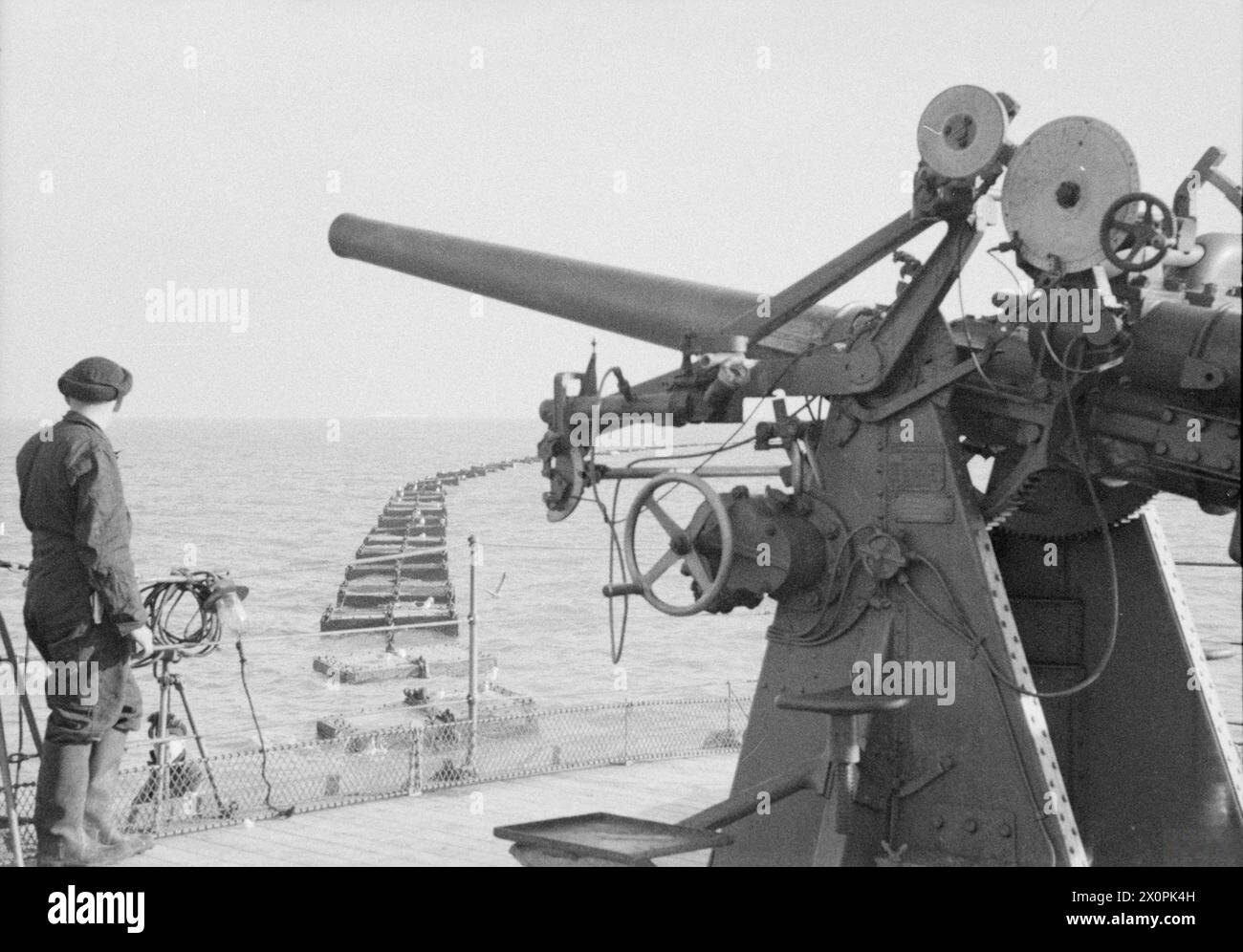 BOOM DEFENCE. 1940, THAMES ESTUARY BOOM DEFENCE, DEFENDING THE PORT OF LONDON, THE NAVAL HARBOURS OF CHATHAM AND SHEERNESS. HEAVY TIDES IN THE ESTUARY AS WELL AS CONSTANT AIR ATTACKS NECESSITATE FREQUENT CHECK UPS ON THE CONDITION OF THE BOOM DEFENCES. - The 3' high-angle gun that guards the gate ship of the estuary boom defence. Spikes and anti-boats baulks are seen behind Stock Photo