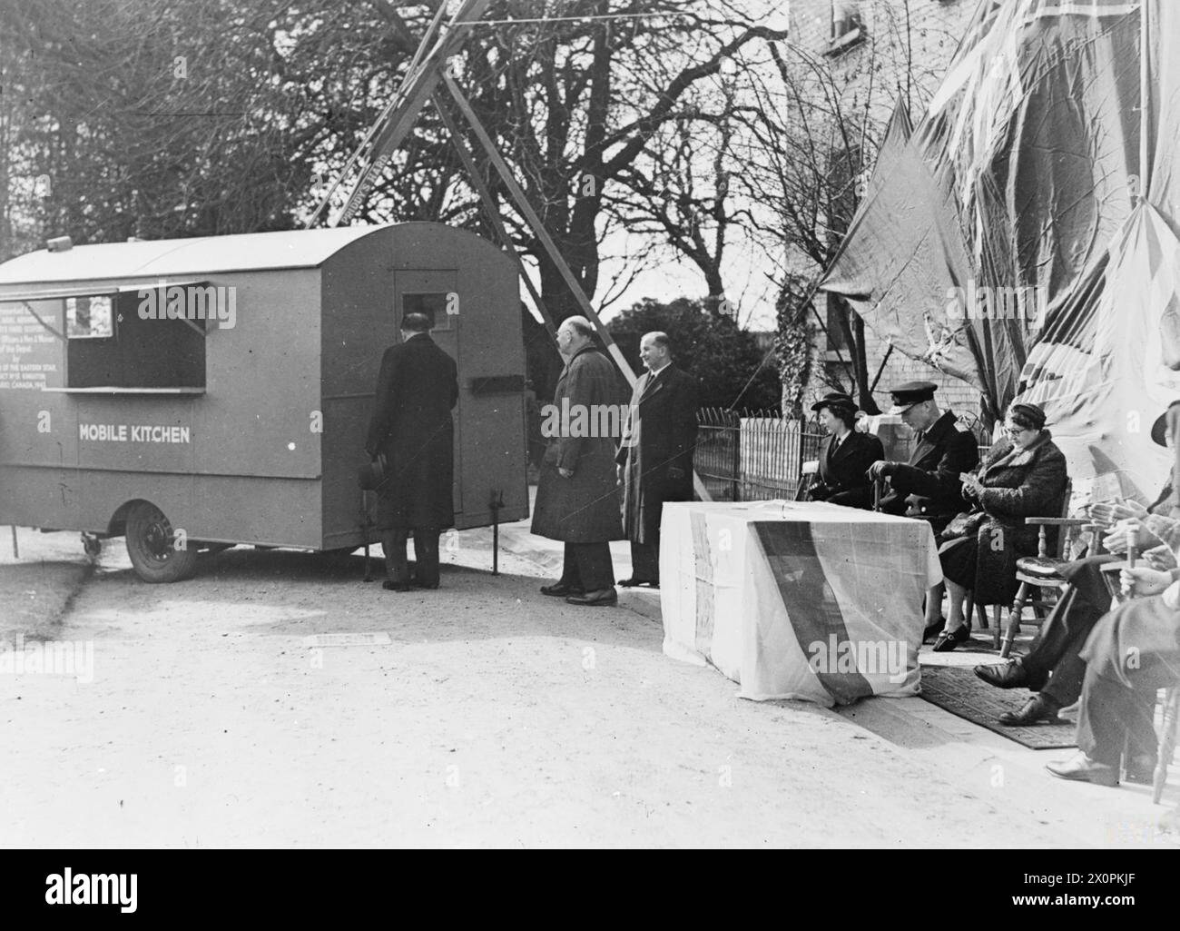 A GIFT FROM KINGSTON ONTARIO. MARCH 1944, GOSPORT. A TRAILER KITCHEN CAR IS THE GIFT OF THE ORDER OF THE EASTERN STAR, DISTRICT NO 13, KINGSTON, ONTARIO, CANADA, TO THE ROYAL NAVAL ARMAMENT DEPOT, GOSPORT. IT WAS PRESENTED BY COL D C UNWIN SIMSON, ADMINISTRATIVE SECRETARY, CANADA, ACTING ON BEHALF OF THE CANADIAN HIGH COMMISSIONER, AND WAS RECEIVED ON BEHALF OF THE DOCKYARD WORKERS BY MR K BOUTWOOD, SUPT ARMAMENT SUPPLY OFFICER. THE C IN C PORTSMOUTH, ADMIRAL SIR CHARLES J C LITTLE, REAR ADMIRAL SIR ARTHUR BROMLEY, OF THE DOMINIONS OFFICE, AND VICE ADMIRAL M L CLARKE, ADMIRAL SUPT PORTSMOUTH D Stock Photo