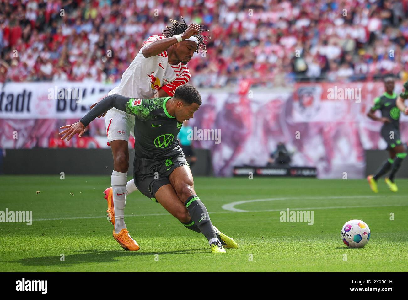 Leipzig, Germany. 13th Apr, 2024. Soccer: Bundesliga, RB Leipzig - VfL Wolfsburg, matchday 29 at the Red Bull Arena. Leipzig player Mohamed Simakan (l) and Wolfsburg's Aster Vranckx in a duel. Credit: Jan Woitas/dpa - IMPORTANT NOTE: In accordance with the regulations of the DFL German Football League and the DFB German Football Association, it is prohibited to utilize or have utilized photographs taken in the stadium and/or of the match in the form of sequential images and/or video-like photo series./dpa/Alamy Live News Stock Photo