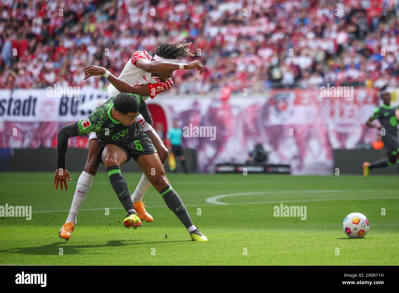 Leipzig, Germany. 13th Apr, 2024. Soccer: Bundesliga, RB Leipzig - VfL Wolfsburg, matchday 29 at the Red Bull Arena. Leipzig player Mohamed Simakan (l) and Wolfsburg's Aster Vranckx in a duel. Credit: Jan Woitas/dpa - IMPORTANT NOTE: In accordance with the regulations of the DFL German Football League and the DFB German Football Association, it is prohibited to utilize or have utilized photographs taken in the stadium and/or of the match in the form of sequential images and/or video-like photo series./dpa/Alamy Live News Stock Photo