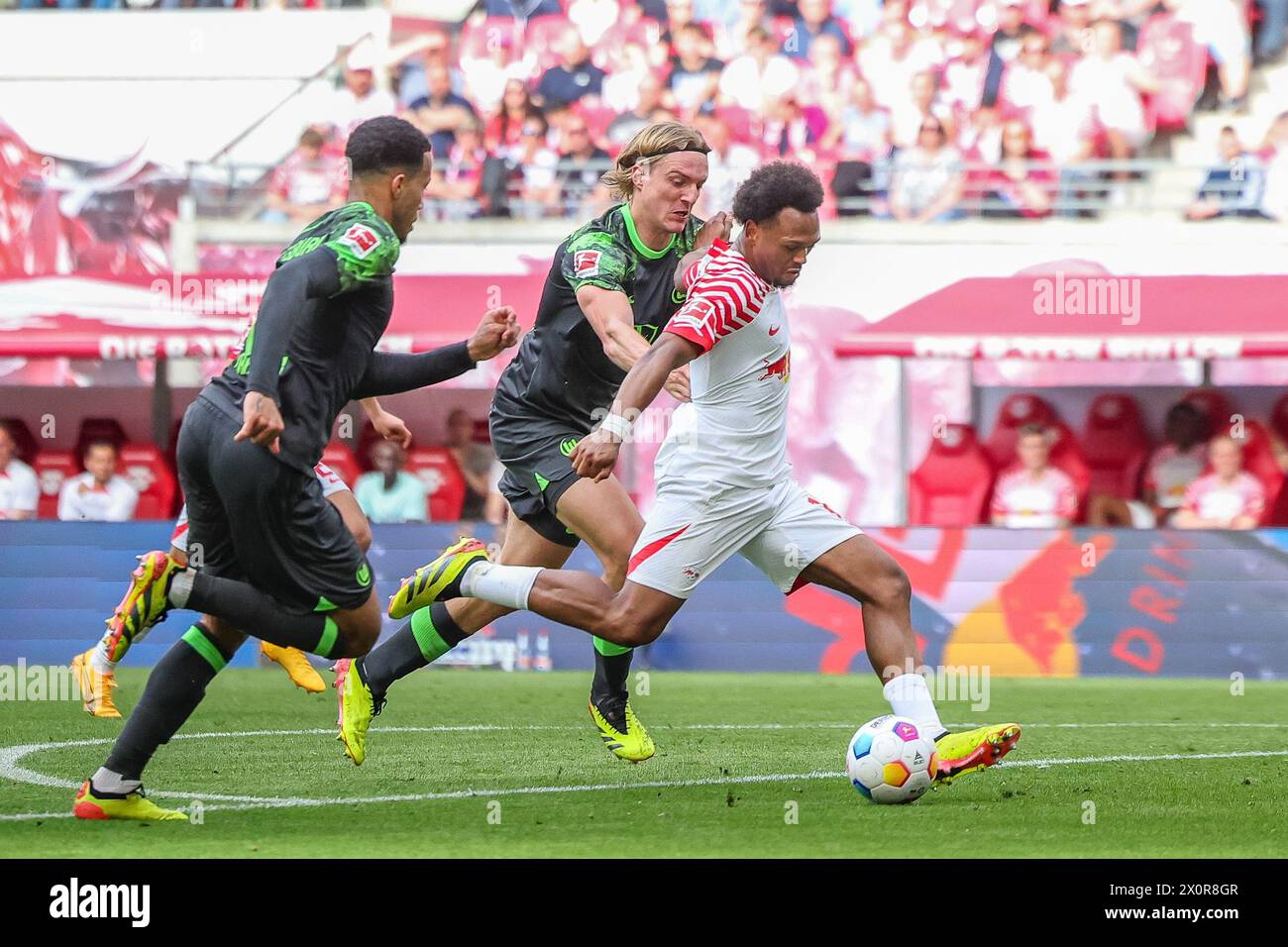 Leipzig, Germany. 13th Apr, 2024. Soccer: Bundesliga, RB Leipzig - VfL Wolfsburg, matchday 29 at the Red Bull Arena. Leipzig player Lois Openda (r) scores to make it 3:0, Wolfsburg's Sebastiaan Bornauw (M) and Aster Vranckx (l) cannot prevent the goal. Credit: Jan Woitas/dpa - IMPORTANT NOTE: In accordance with the regulations of the DFL German Football League and the DFB German Football Association, it is prohibited to utilize or have utilized photographs taken in the stadium and/or of the match in the form of sequential images and/or video-like photo series./dpa/Alamy Live News Stock Photo