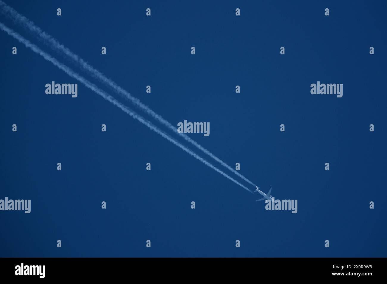Airplane in the blue sky with contrail Stock Photo - Alamy