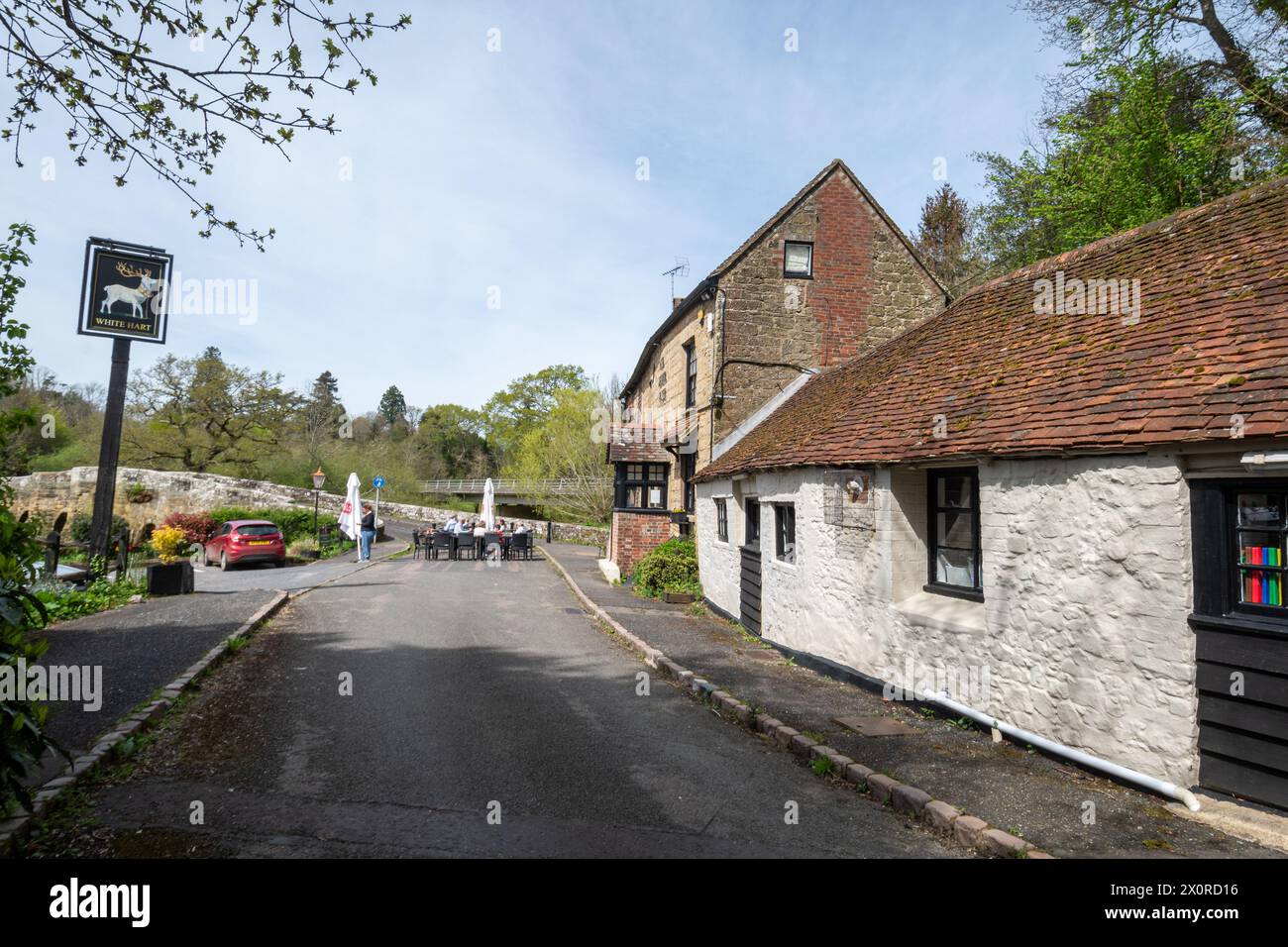 The White Hart pub beside Stopham Bridge with people sitting outside in Stopham village, West Sussex, England, UK Stock Photo