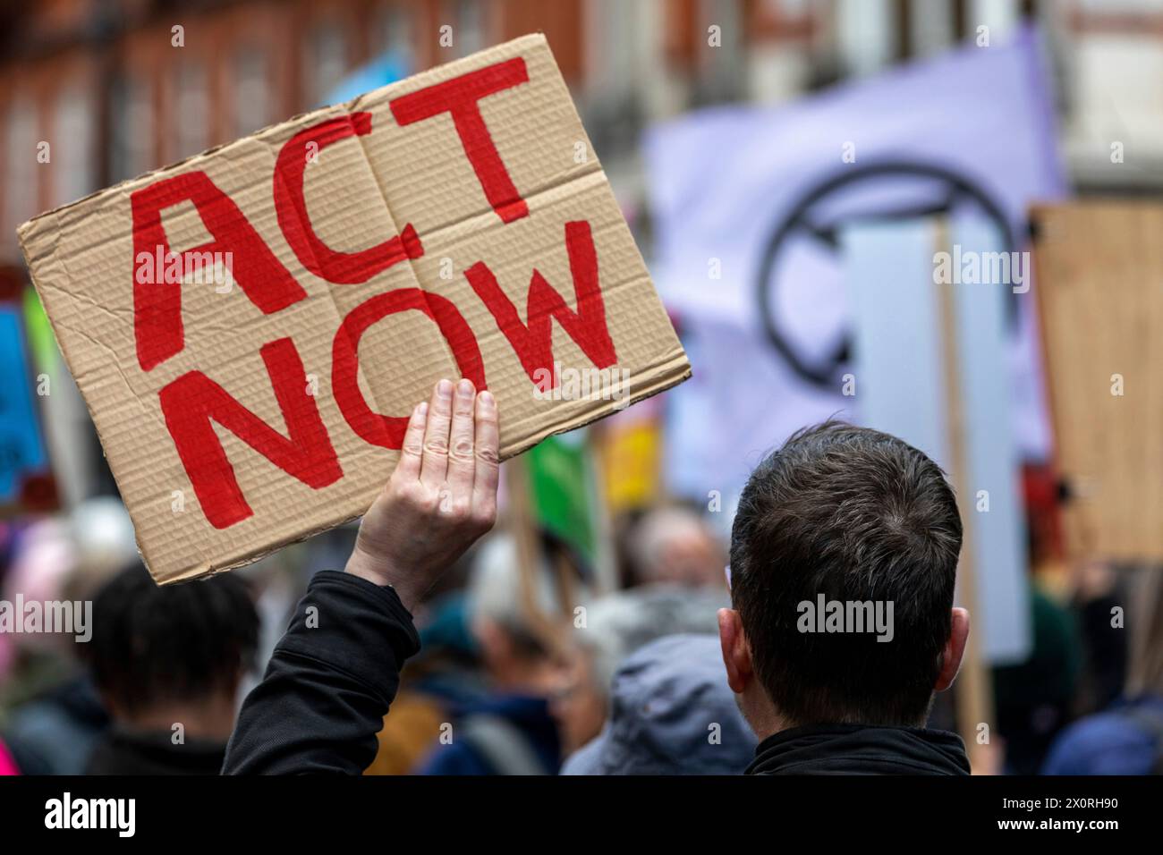 A climate change rally in central London in 2022, with a protestor carrying a cardboard sign with the words 'Act Now' written in red. Stock Photo