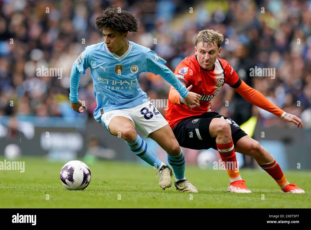 Manchester, UK. 13th Apr, 2024. Rico Lewis of Manchester City (L) is challenged by Alfie Doughty of Luton Town during the Premier League match at the Etihad Stadium, Manchester. Picture credit should read: Andrew Yates/Sportimage Credit: Sportimage Ltd/Alamy Live News Stock Photo