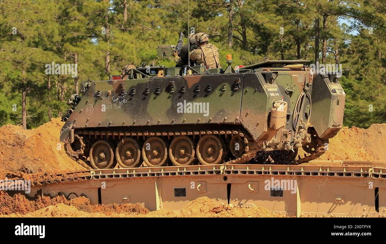 A M113 Armored Personnel Carrier, assigned to 1st Armored Brigade Combat Team, breaches a tank ditch using a Joint Assault Bridge (JAB), during Marne Focus at Fort Stewart, Georgia, Apr. 12, 2024. Marne Focus is a key component of the division’s efforts to train and equip forces to maintain our competitive advantage, and fight and win in conflict. (U.S. Army photo by Pfc. Santiago Lepper) Stock Photo
