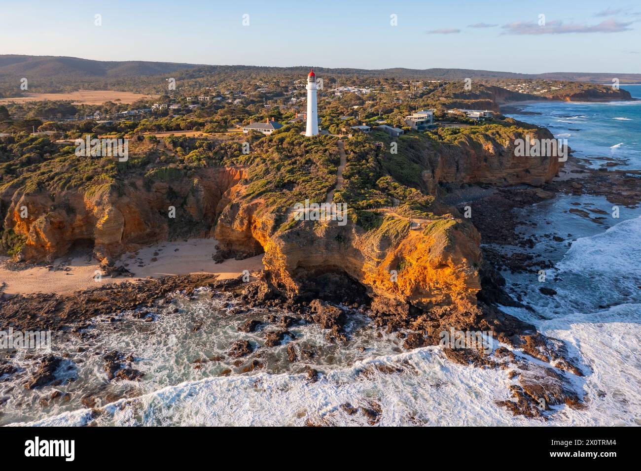 Aerial view of a tall white lighthouse perched on rugged cliffs above ...