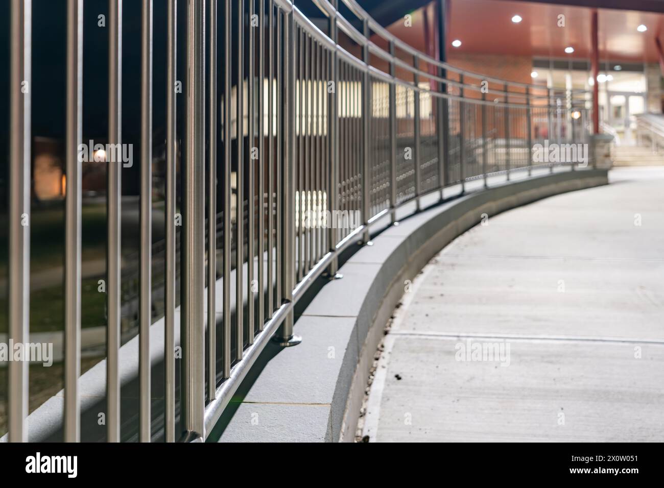 Example of a stainless steel railing along a concrete sidewalk, at the top of retaining wall. Stock Photo