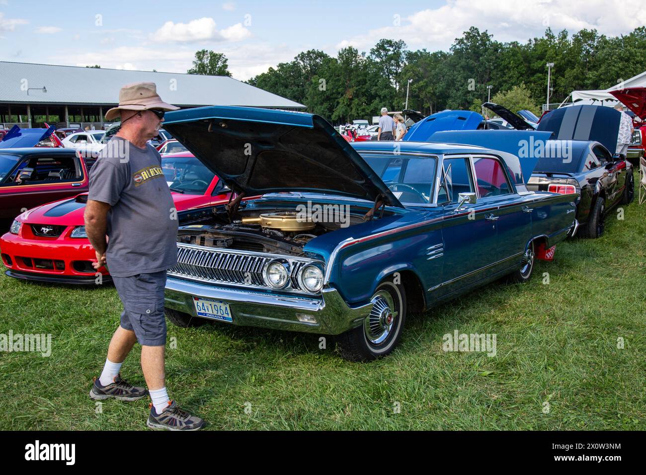 A man walks past a blue 1964 Mercury Monterey sedan on display in a car show at the Allen County Fairgrounds in Fort Wayne, Indiana, USA. Stock Photo