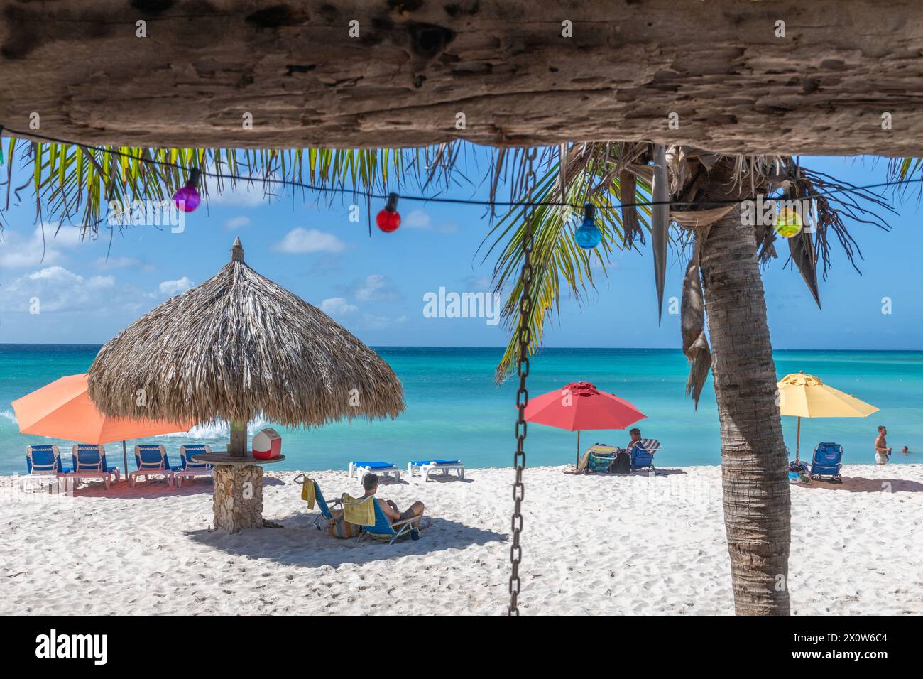 Arashi Beach Aruba with beach umbrellas and beach goers viewed from cafe Stock Photo