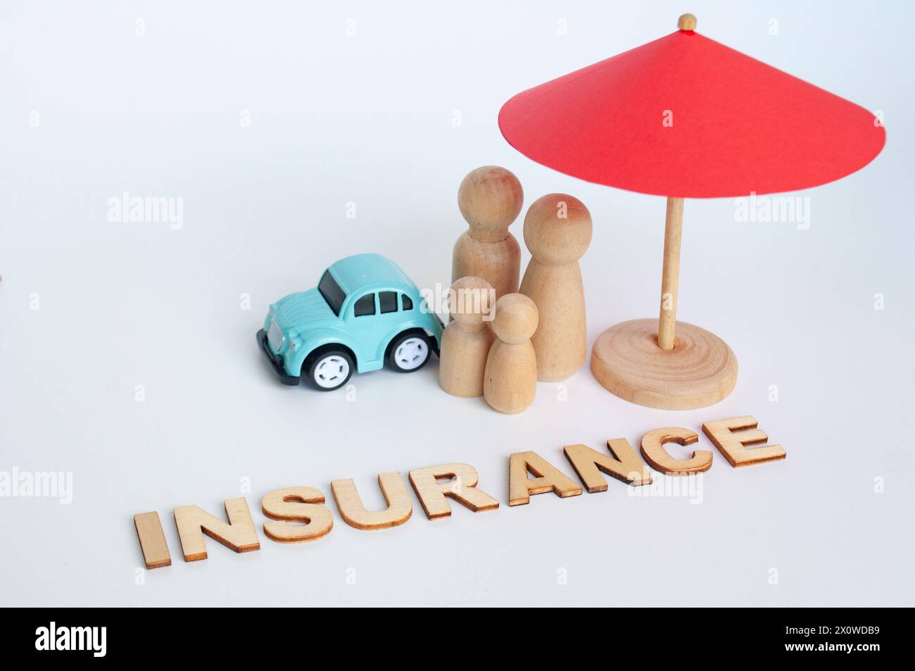 Red umbrella, wooden family doll figures and a car. Insurance coverage concept. Stock Photo