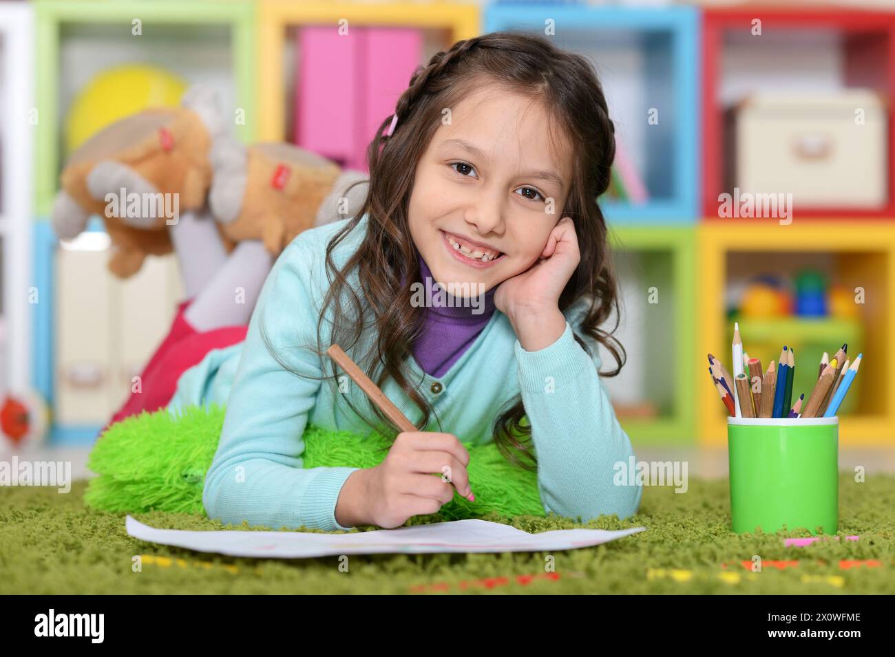 Portrait of cute little girl drawing while lying Stock Photo - Alamy