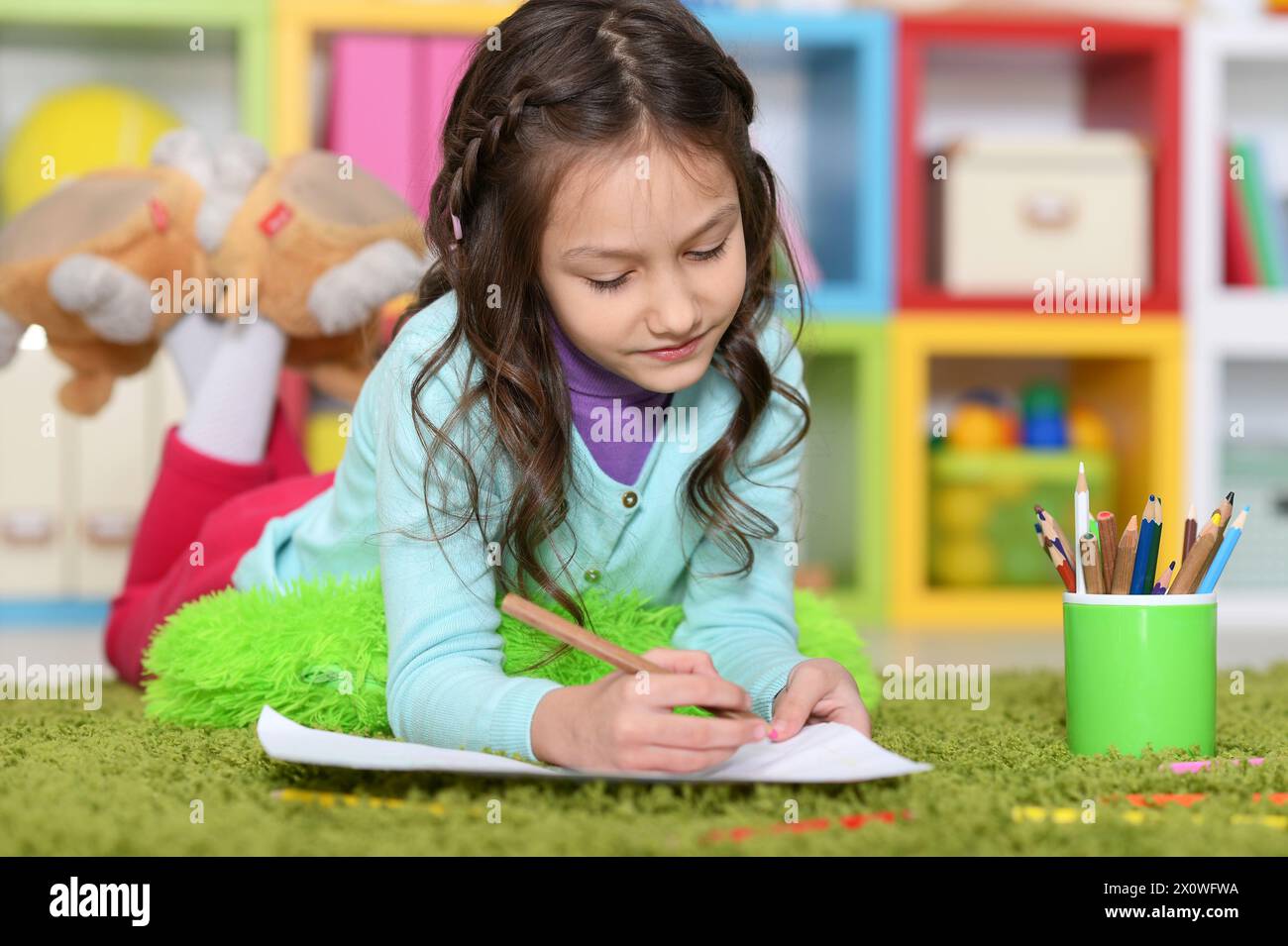 Portrait of cute little girl drawing while lying Stock Photo - Alamy