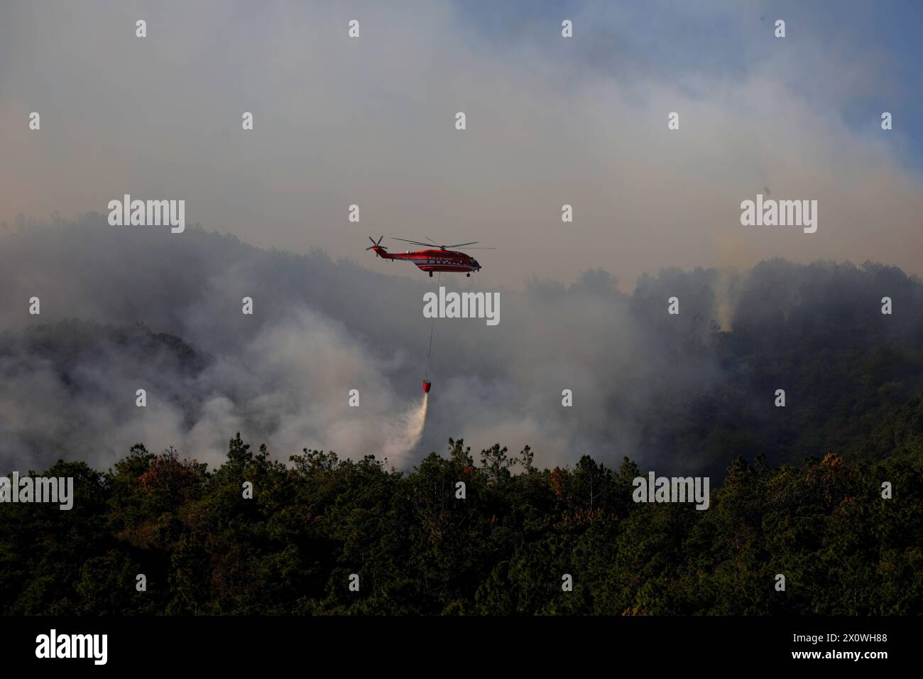 (240414) -- JINNING, April 14, 2024 (Xinhua) -- A fire-fighting helicopter operates at the site of a forest fire in Jinning District of Kunming, southwest China's Yunnan Province, April 14, 2024. More than 2,300 people are battling a forest fire that has raged in southwest China's Yunnan Province since Friday, local authorities said Sunday. The fire started at around 4 p.m. Friday in Diantou Village in Jinning District of the capital city Kunming. No casualties have been reported so far. Officials confirmed the mobilization of 46 excavators and two helicopters to help put out the blaze. ( Stock Photo