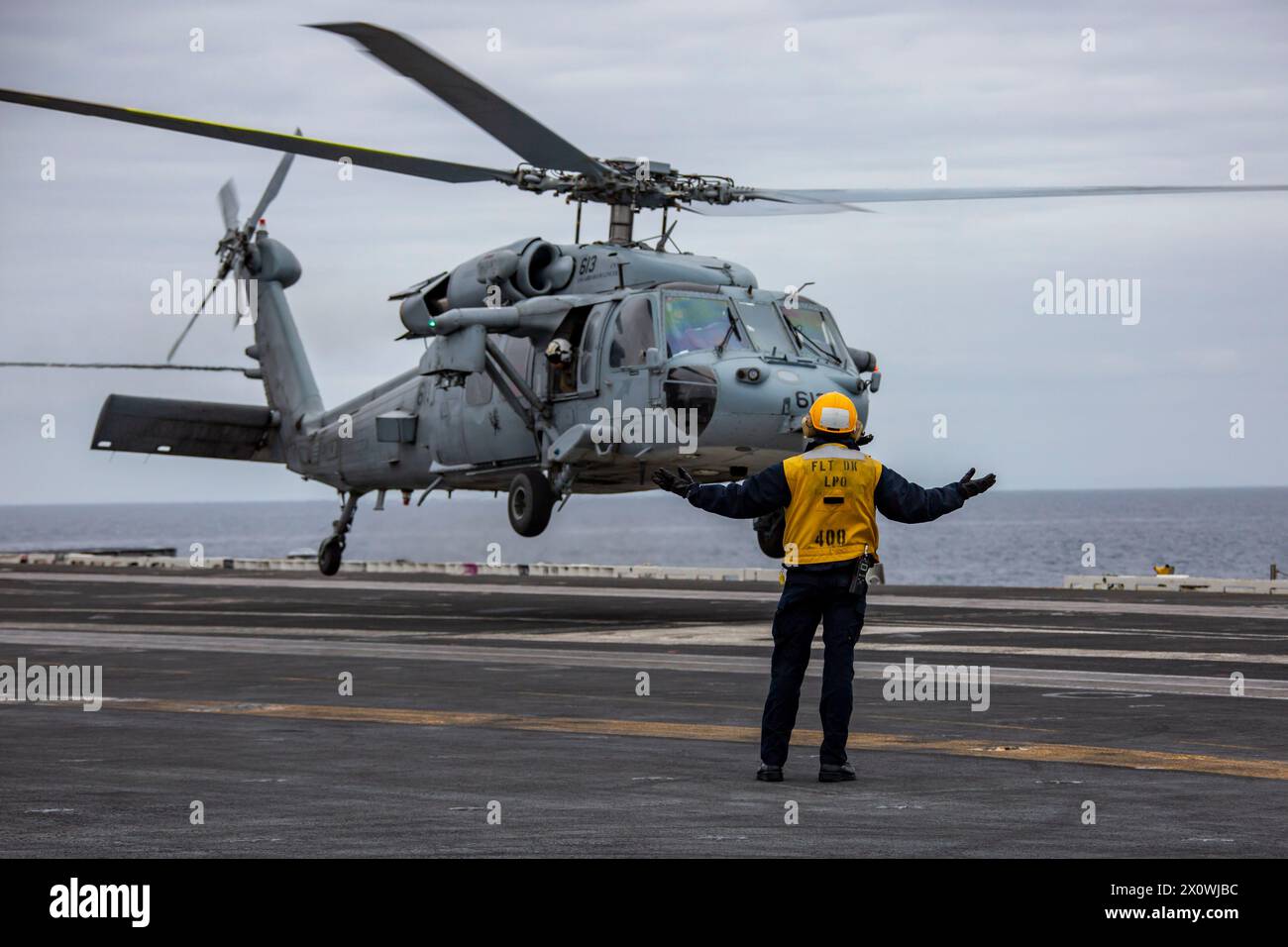 240413-N-YF131-1016 PACIFIC OCEAN (April 13, 2024) Aviation Boatswain’s Mate (Handling) 1st Class Kevin Miller, from Belleville, Ill., directs an MH-6 Stock Photo