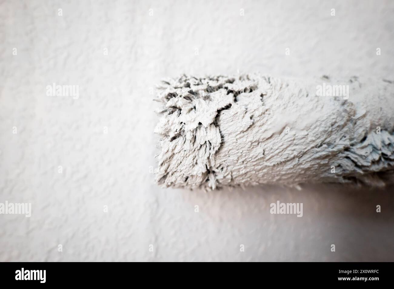 Paint roller extendable pole over painted woodchip wallpaper wall