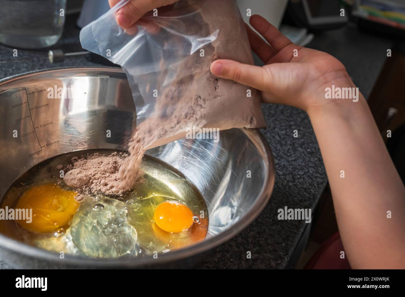 Child hands adding cupcake mix powder to a mixer bowl to make a dessert ...