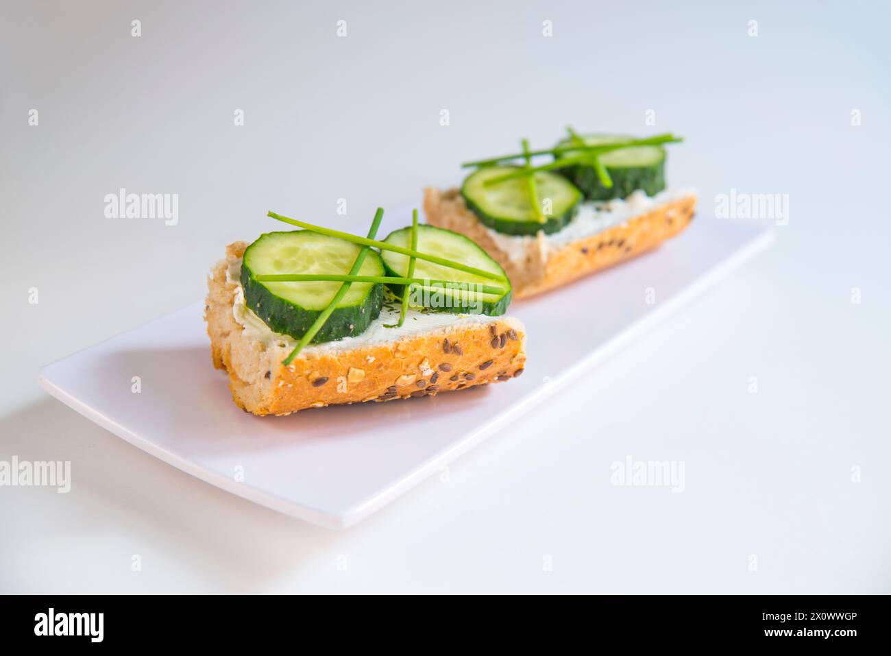 Vegetarian tapa: cucumber and spring onion and cheese cream on toast. Stock Photo