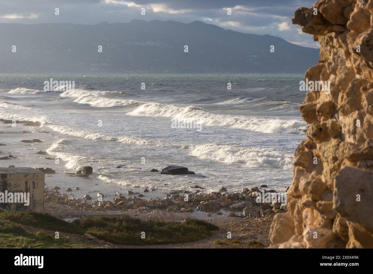 Windy day at the beach. Big waves. view from a rocky spot above tha beach. Mountains in the backround. Stock Photo