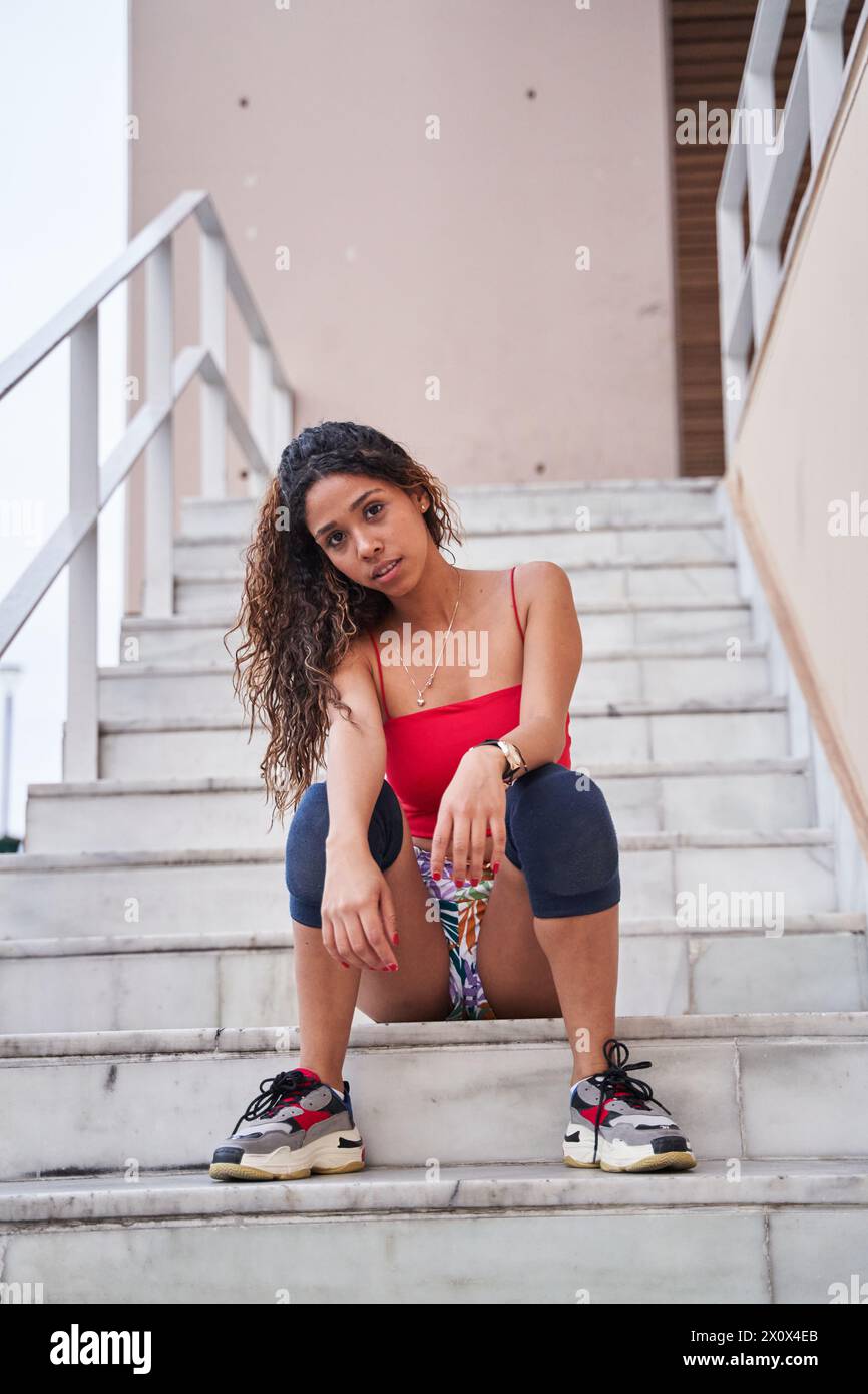 young latina sitting on the stairs looking at the camera Stock Photo ...