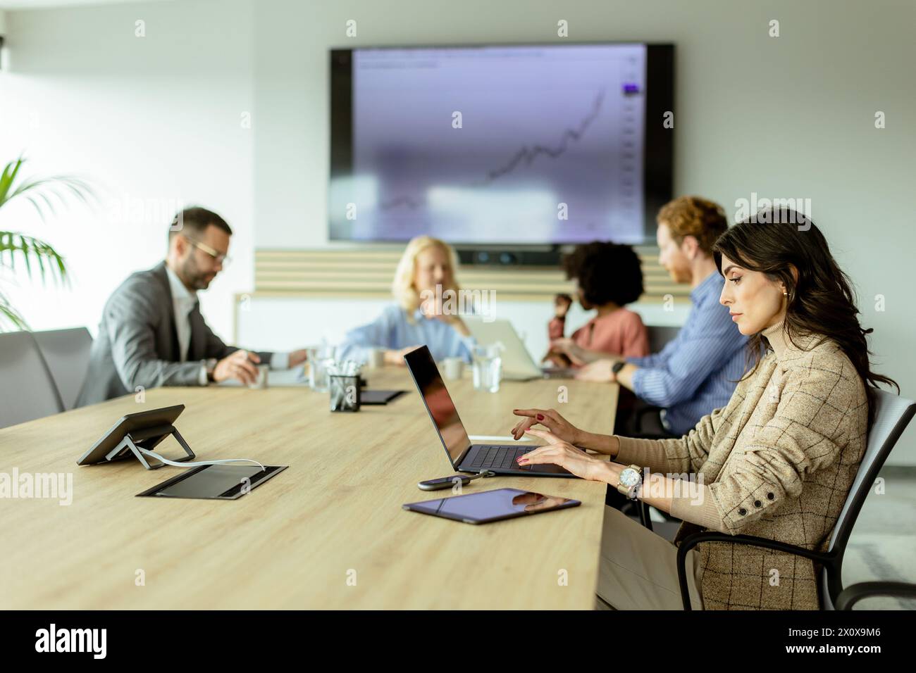 A professional team analyzes growth trends in a modern conference room with a digital display. Stock Photo