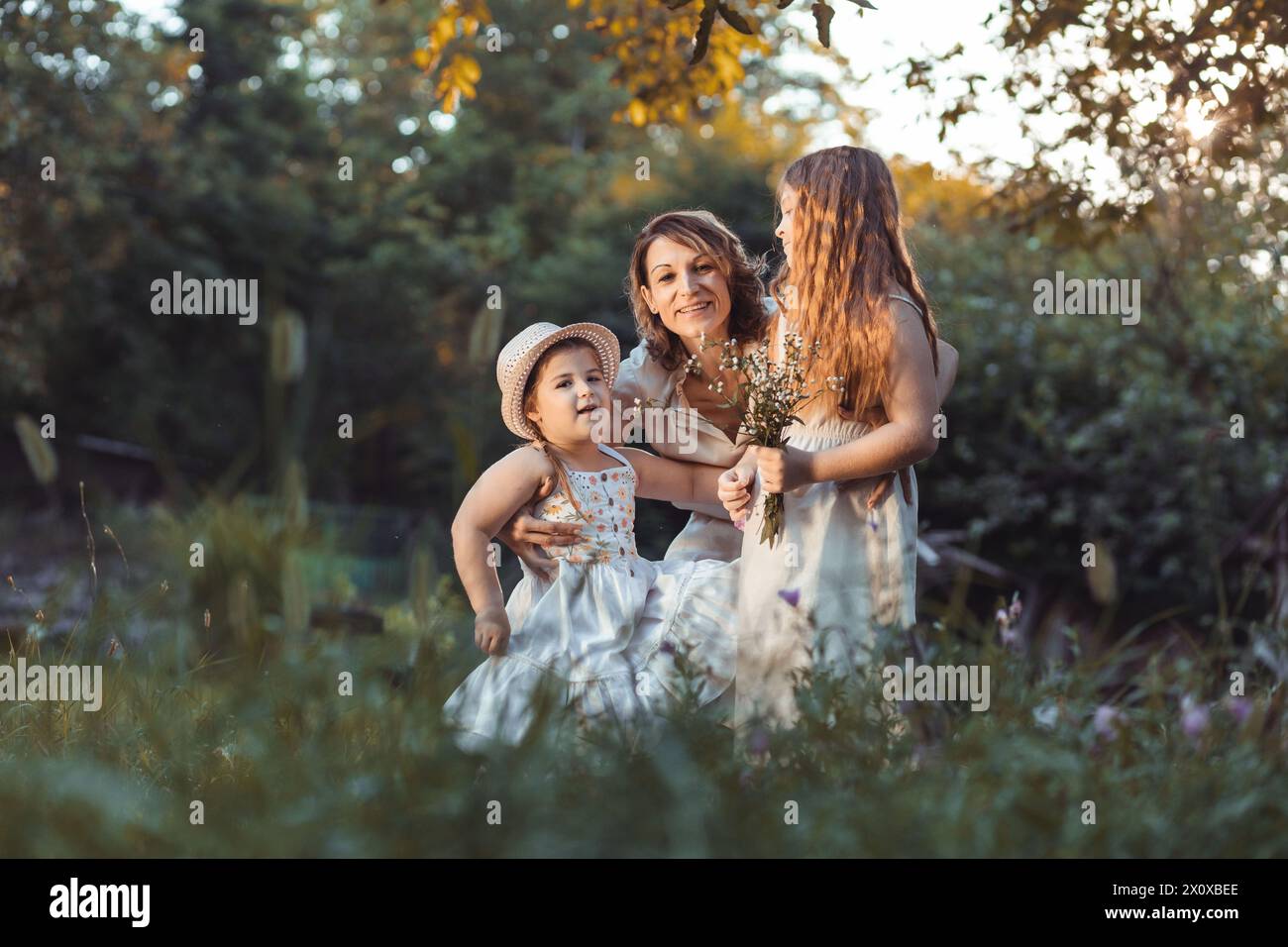 Mother and daughters enjoying a sunny weather in nature Stock Photo