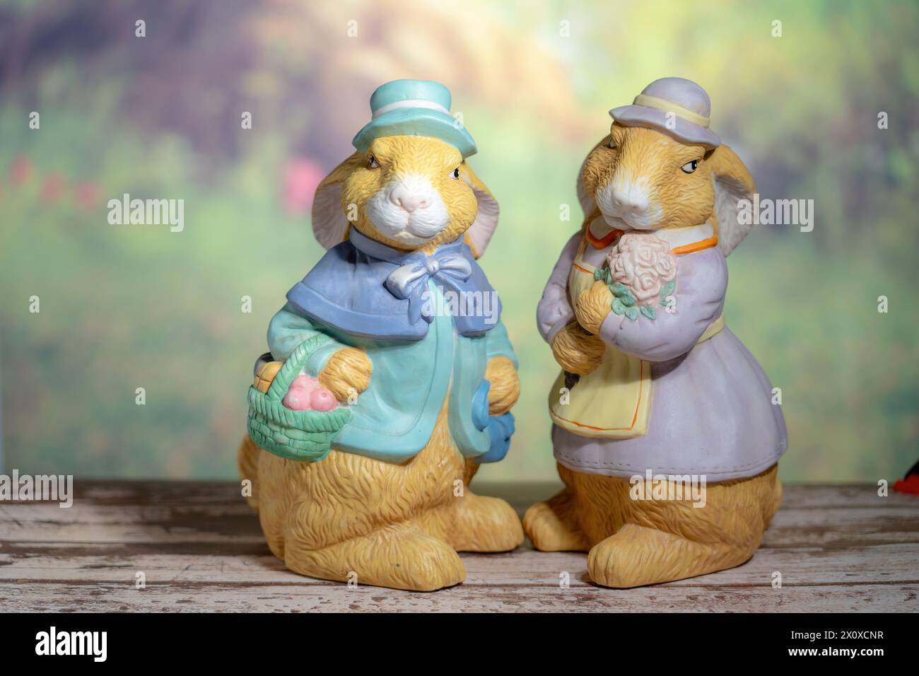 Two statues of rabbits Husband and wife holding flowers. Easter, Pascha ...