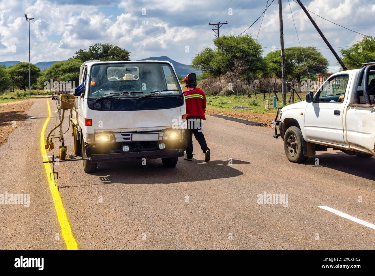 african men repairing and maintaining faded road markings on the highway, repainting yellow markings for traffic safety Stock Photo