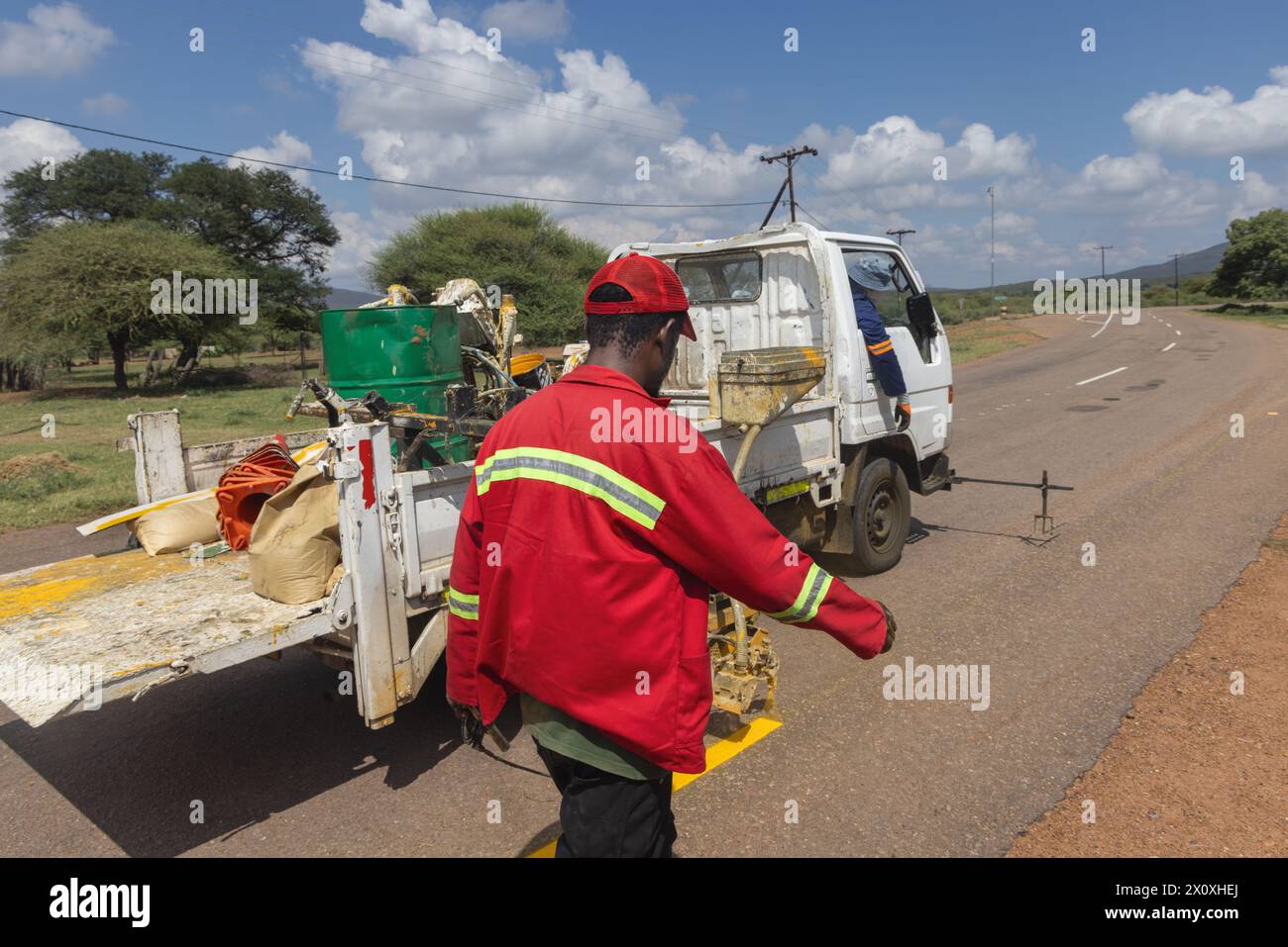 african men repairing and maintaining faded road markings on the highway, repainting yellow markings for traffic safety Stock Photo