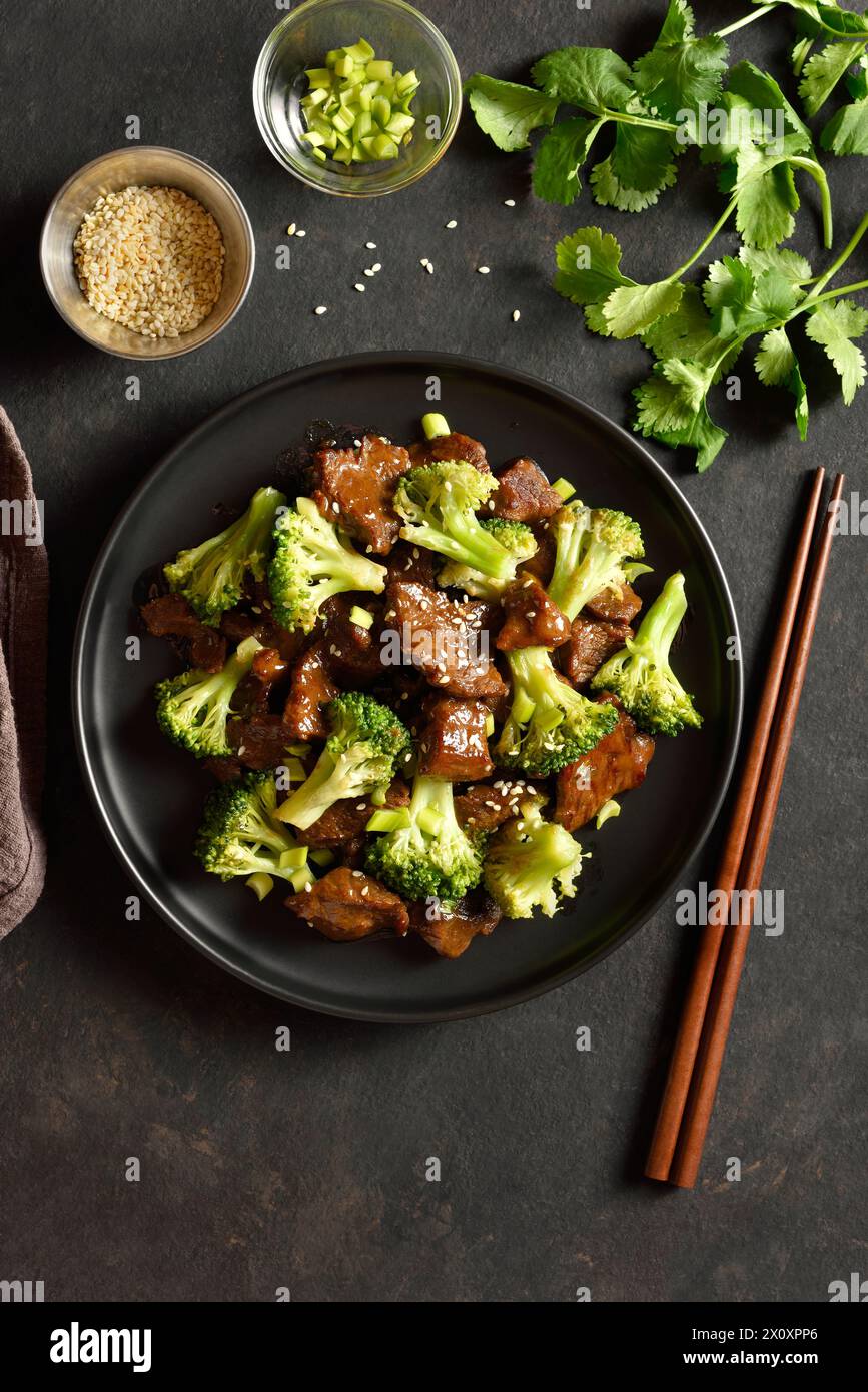 Beef with broccoli on plate over dark stone background. Thinly sliced beef meat with roasted broccoli. Top view, flat lay Stock Photo