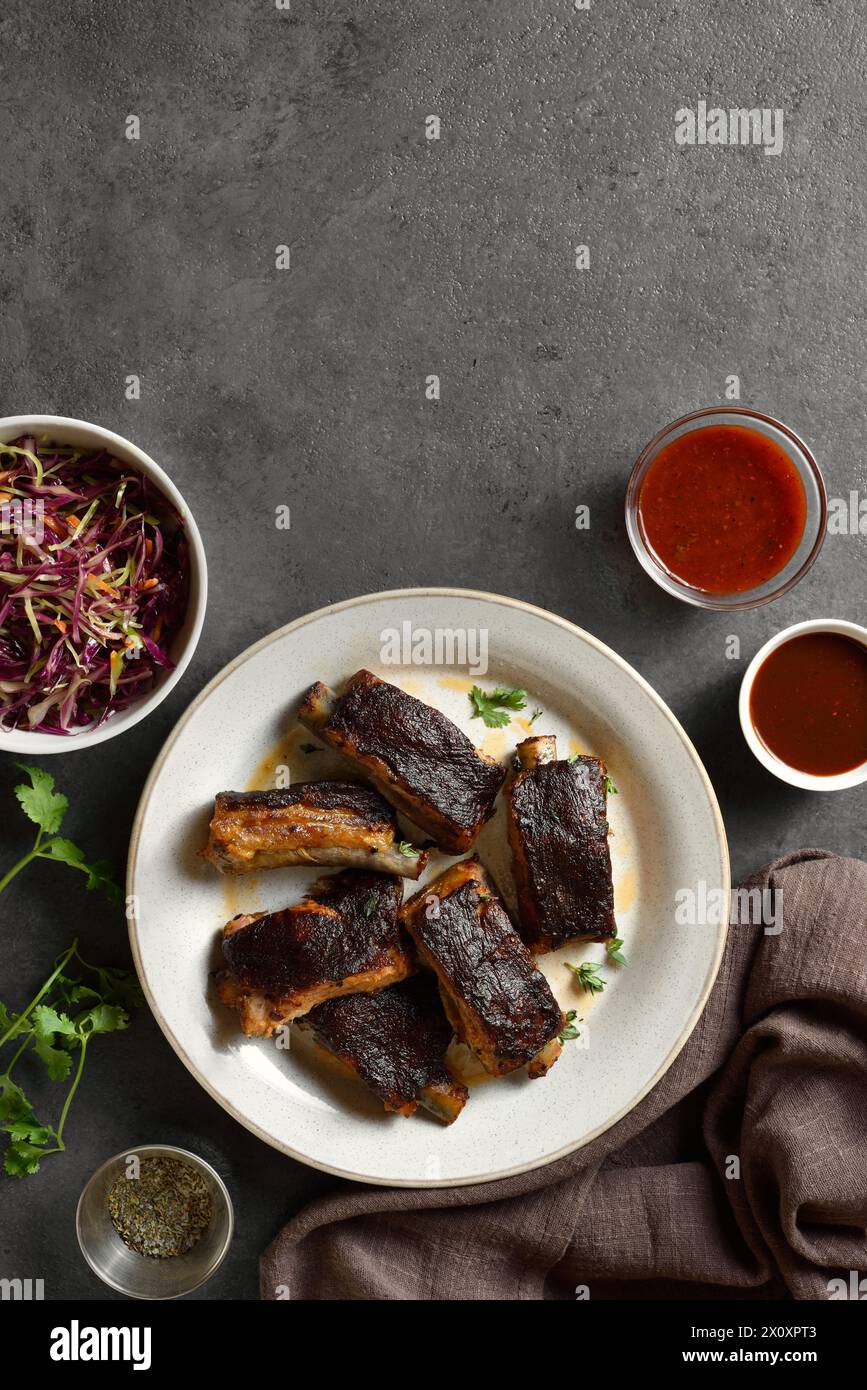 Pork ribs on plate over dark stone background with copy space. Top view, flat lay Stock Photo